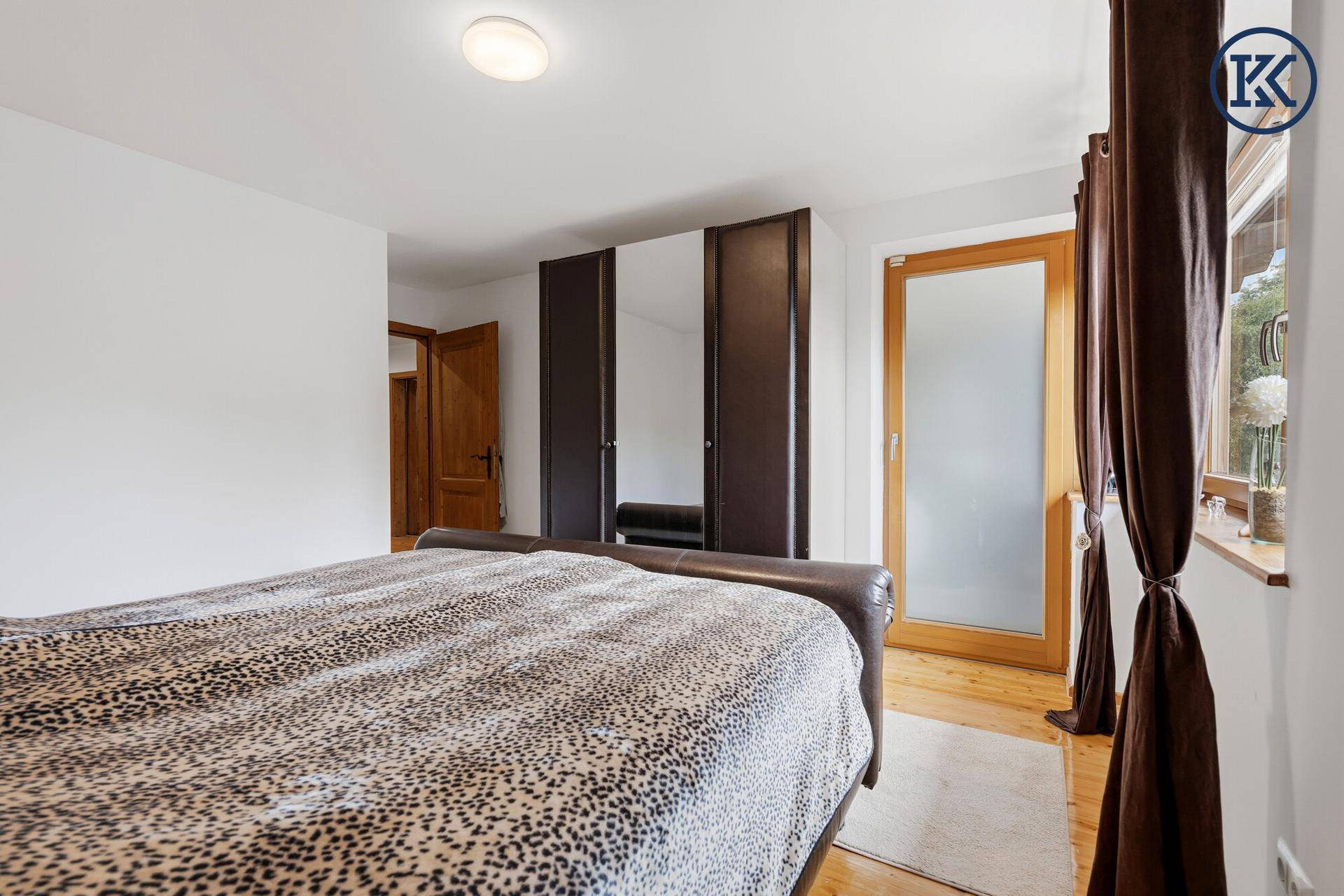 Schlafzimmer mit Doppelbett, Holzboden und Zugang zu einem Balkon oder Terrasse.