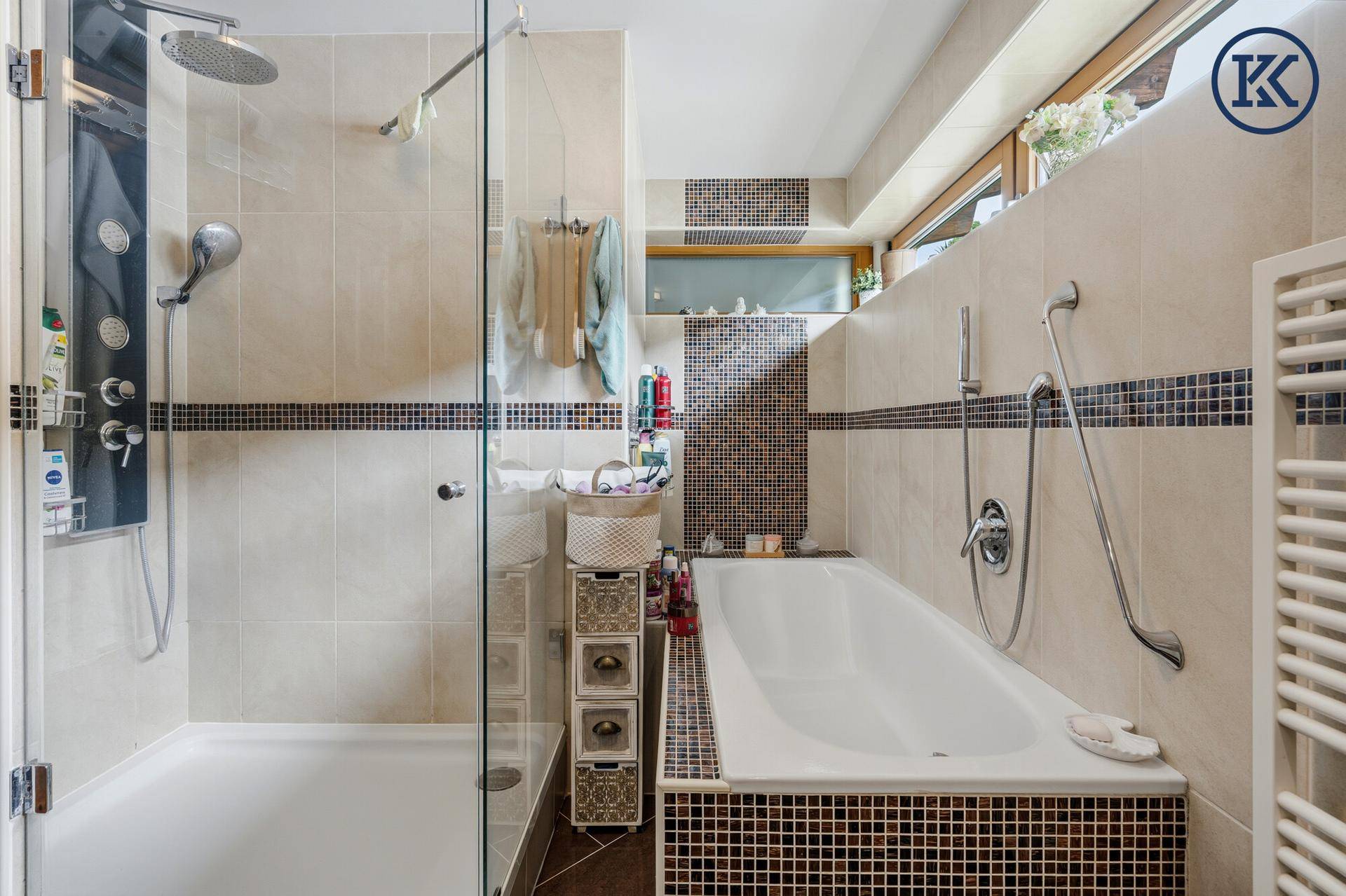 Badezimmer mit Badewanne, Duschkabine und Fliesen in warmen Farbtönen.