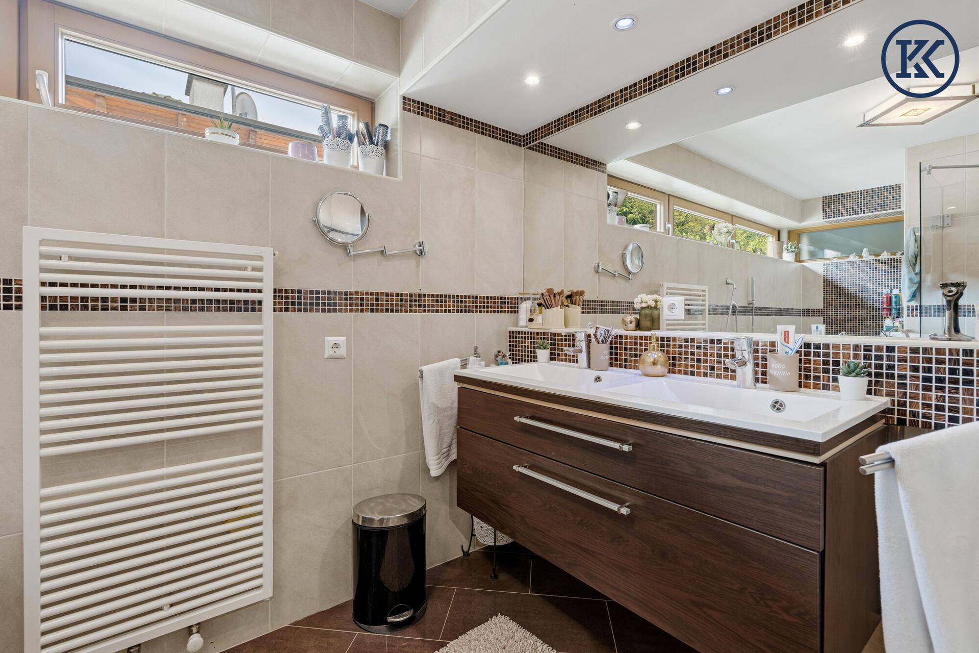 Modernes Badezimmer mit Doppelwaschbecken, Fliesen und beheiztem Handtuchhalter.