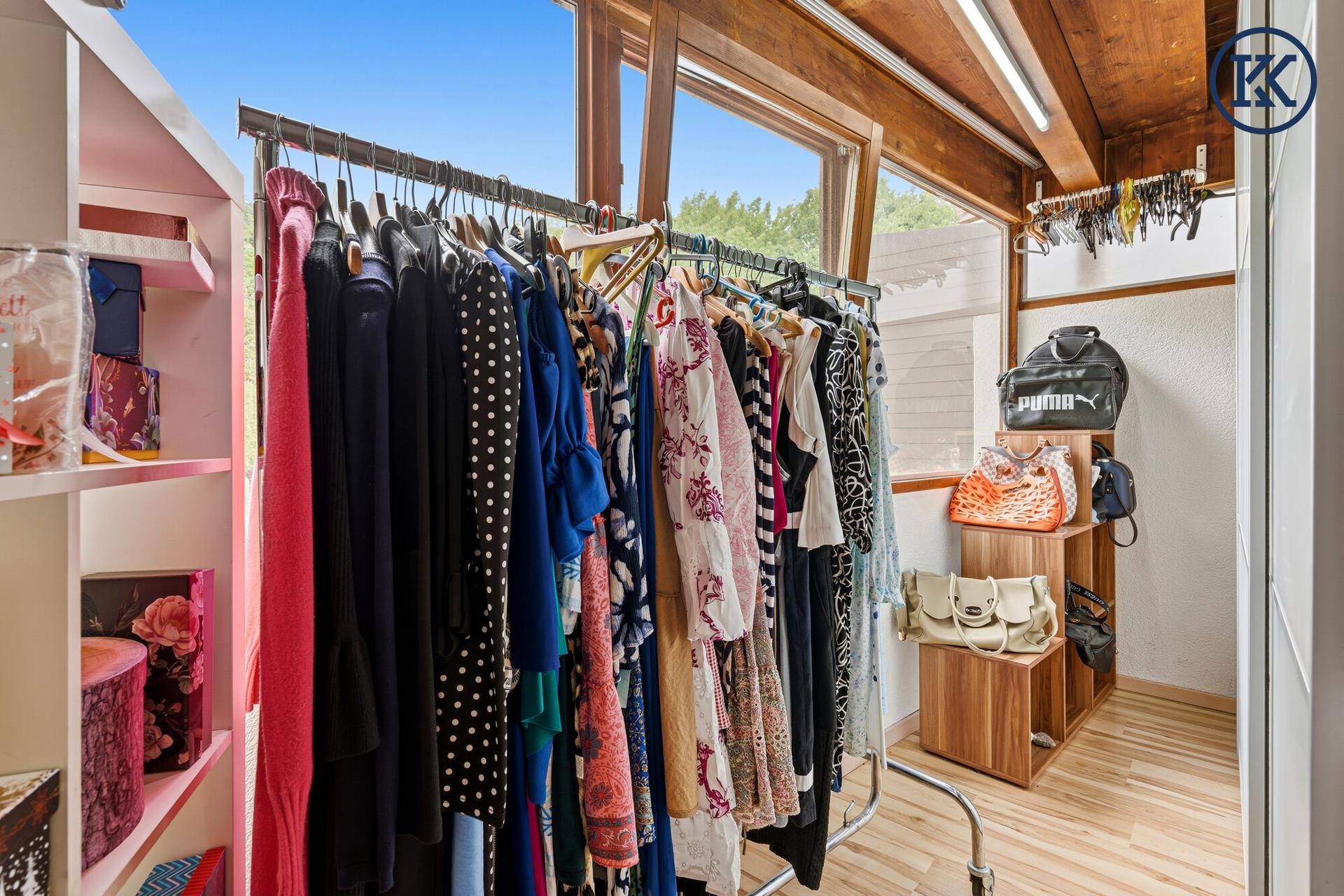 Begehbarer Kleiderschrank mit Kleiderstangen und Regalen, viel Tageslicht.