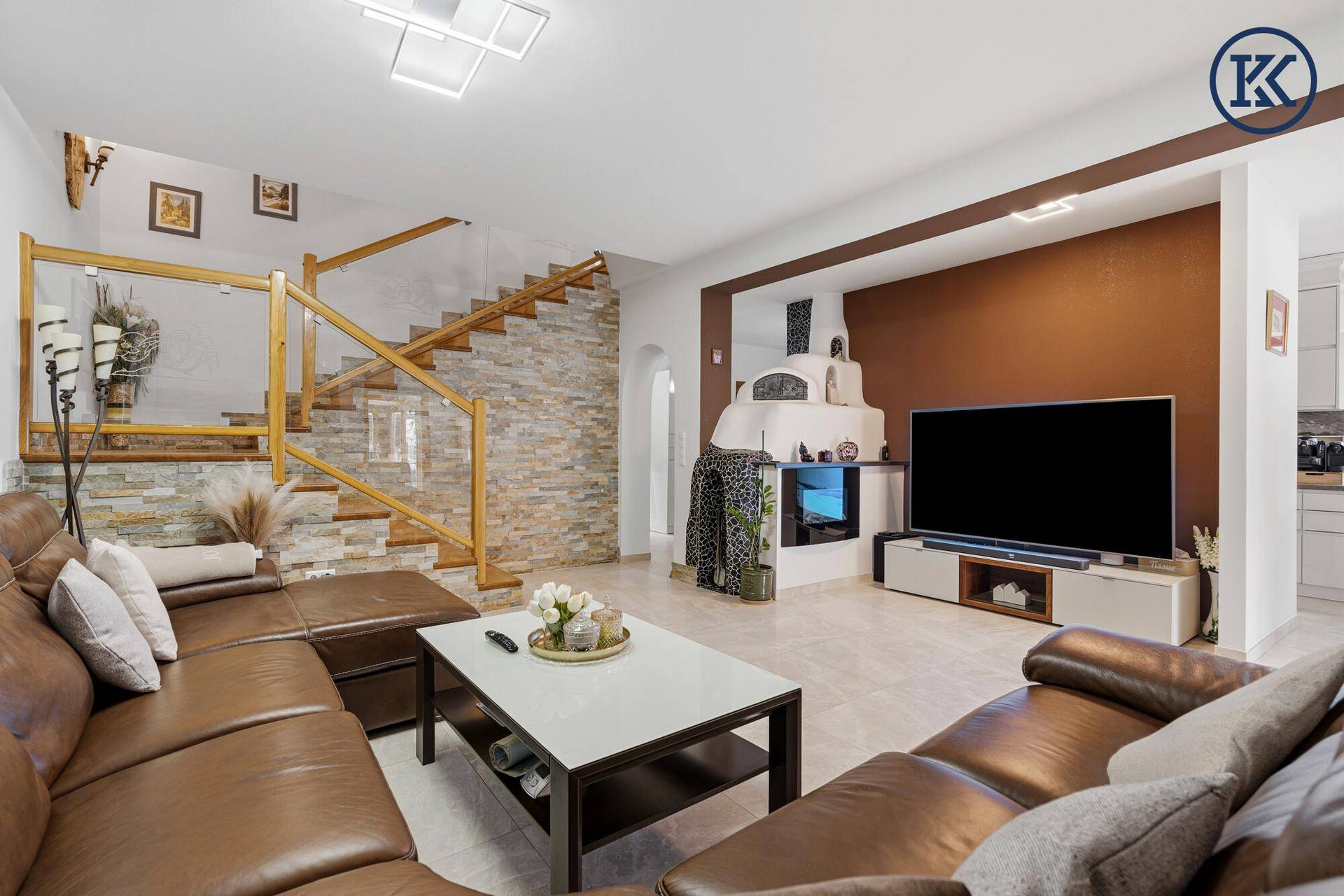 Geräumiges Wohnzimmer mit Ledersofa, Kamin und Zugang zur Treppe.