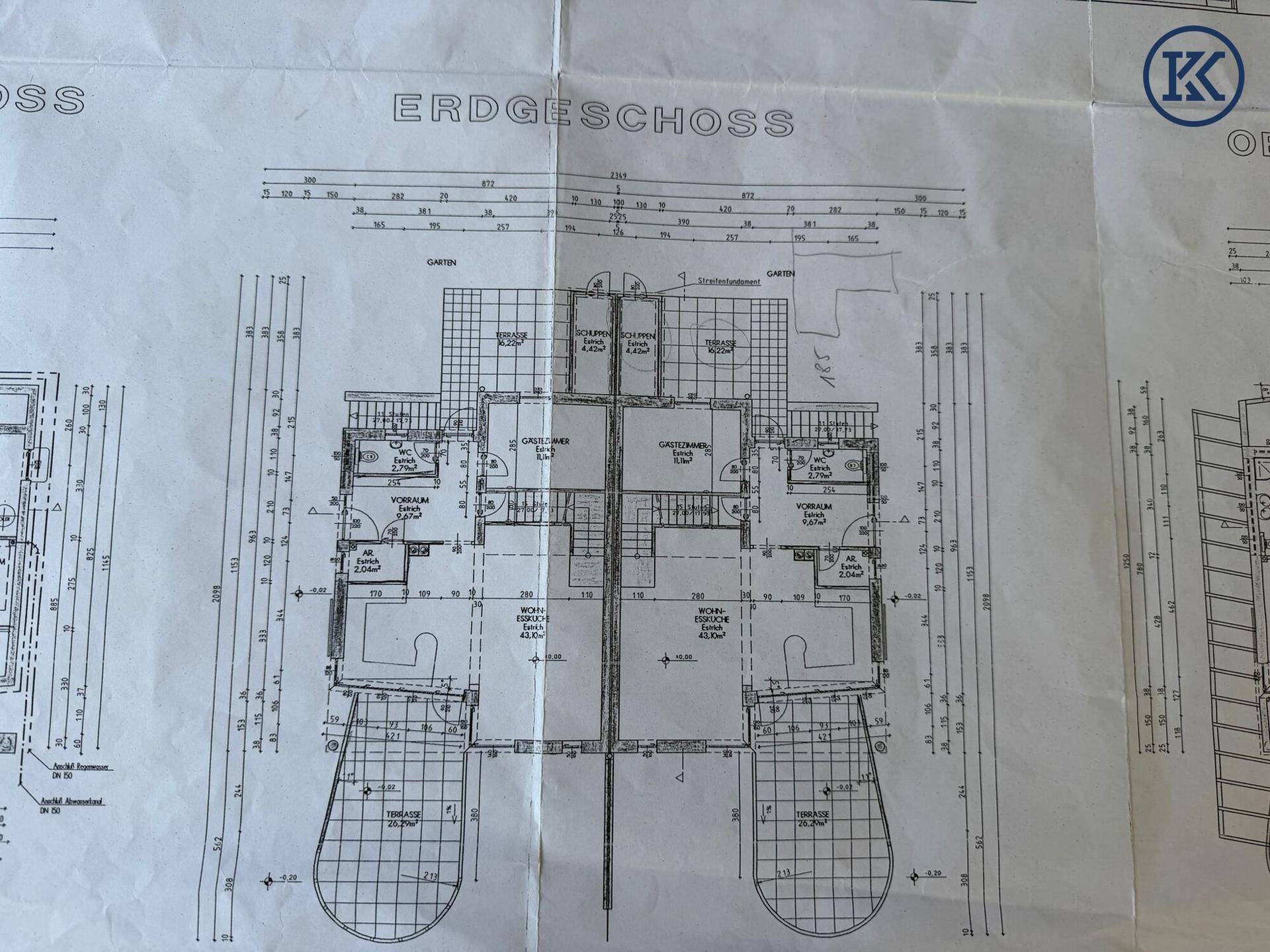 Grundriss des Erdgeschosses mit offenem Wohn-Essbereich, Küche, Gästezimmer und Zugang zu zwei Terrassen.