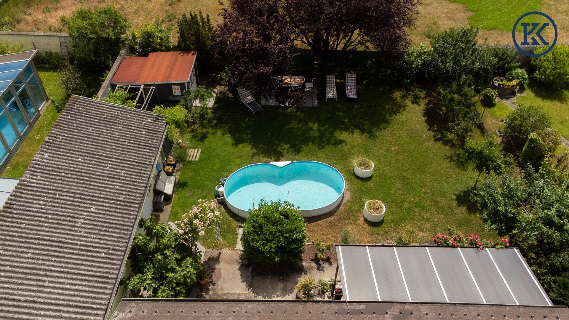 Rückansicht des Grundstücks mit weitläufigem Garten, Pool, Gartenhaus und gemütlichem Sitzbereich.