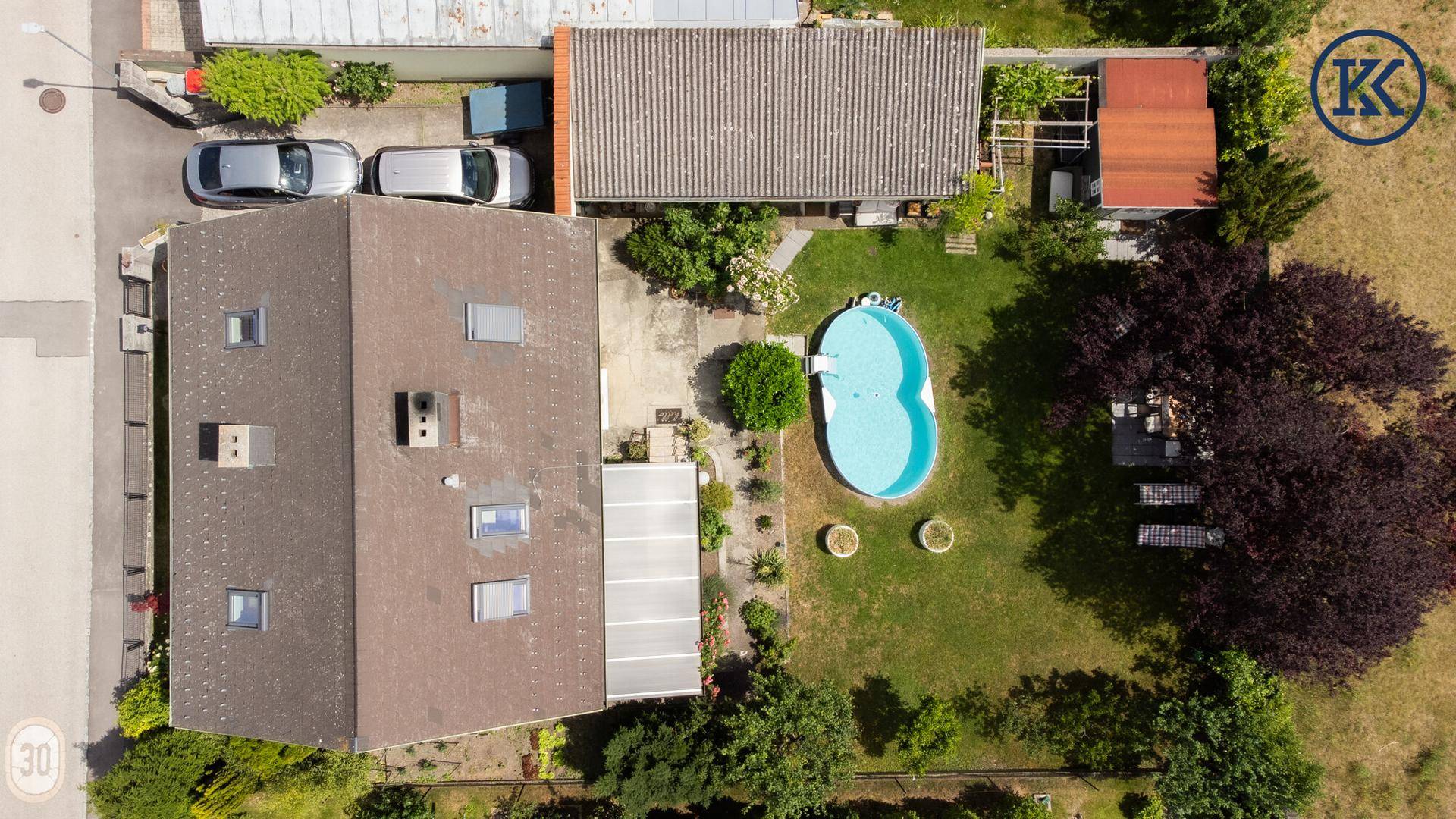 Gesamtansicht des Anwesens von oben mit Wohnhaus, großem Garten, Pool und Parkplätzen.