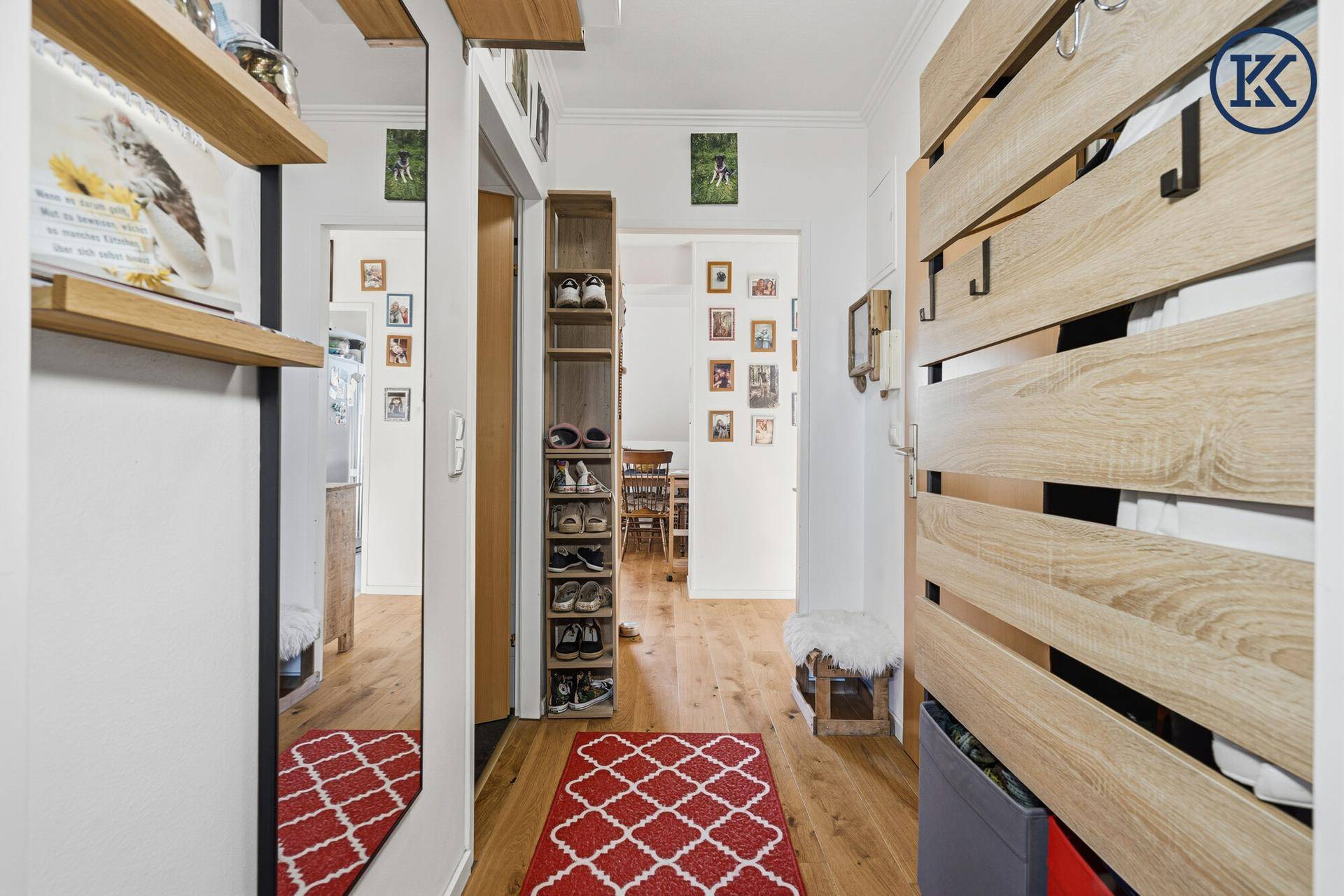 Langer Flur mit Holzfußboden, Schuhregal und vielen Familienfotos an der Wand.