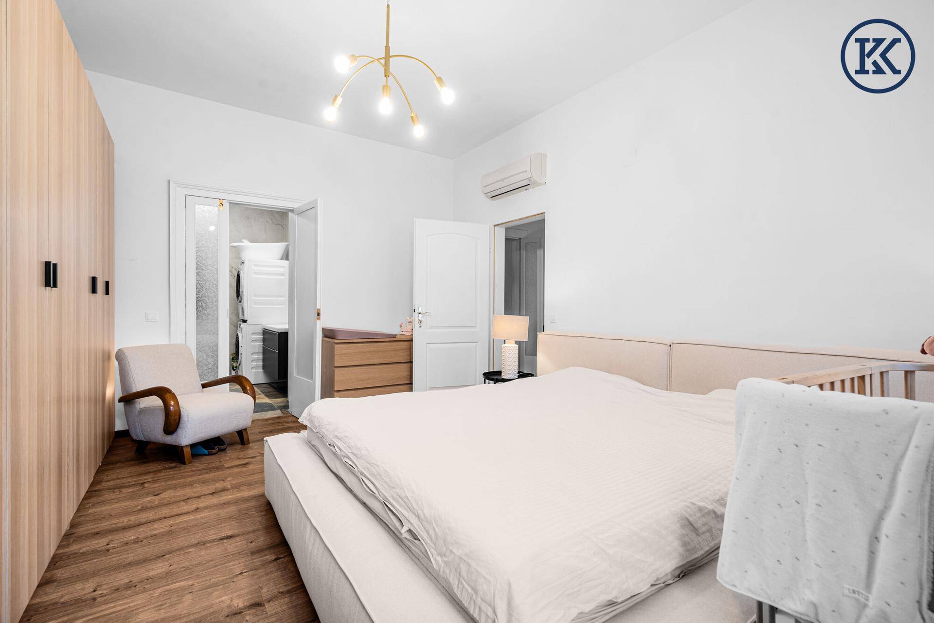 Schlafzimmer mit Holzboden, Einbauschränken und Zugang zu einem begehbaren Kleiderschrank.