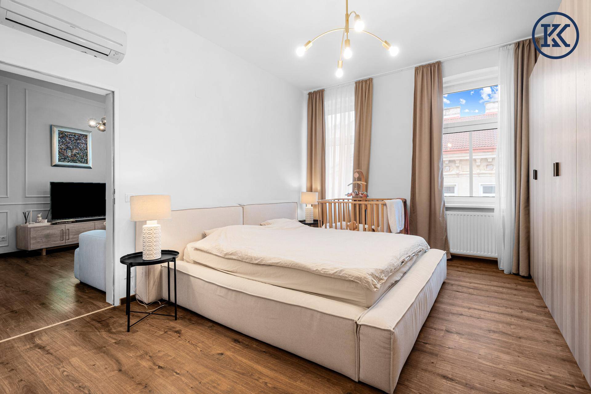 Helles Schlafzimmer mit großem Bett, Holzboden und einem Fenster mit Stadtblick.