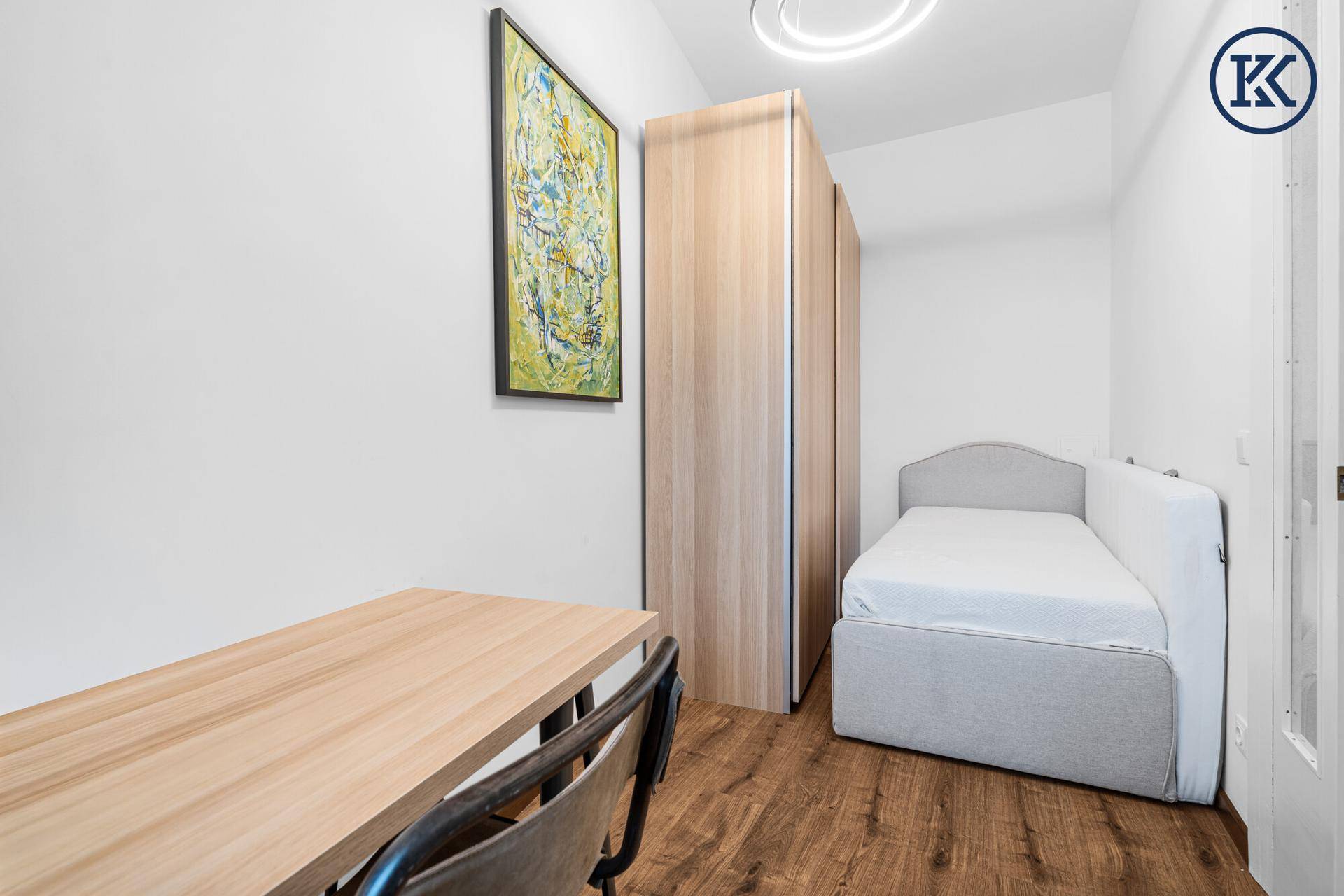 Kleines Schlafzimmer mit Holzboden, Schrank und einem Schreibtisch für Home-Office.