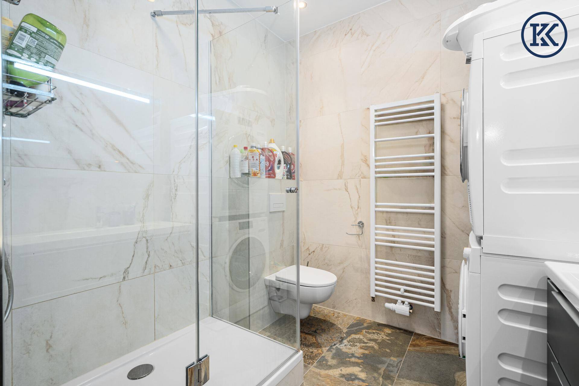 Badezimmer mit begehbarer Dusche, wandhängender Toilette und beheiztem Handtuchhalter.