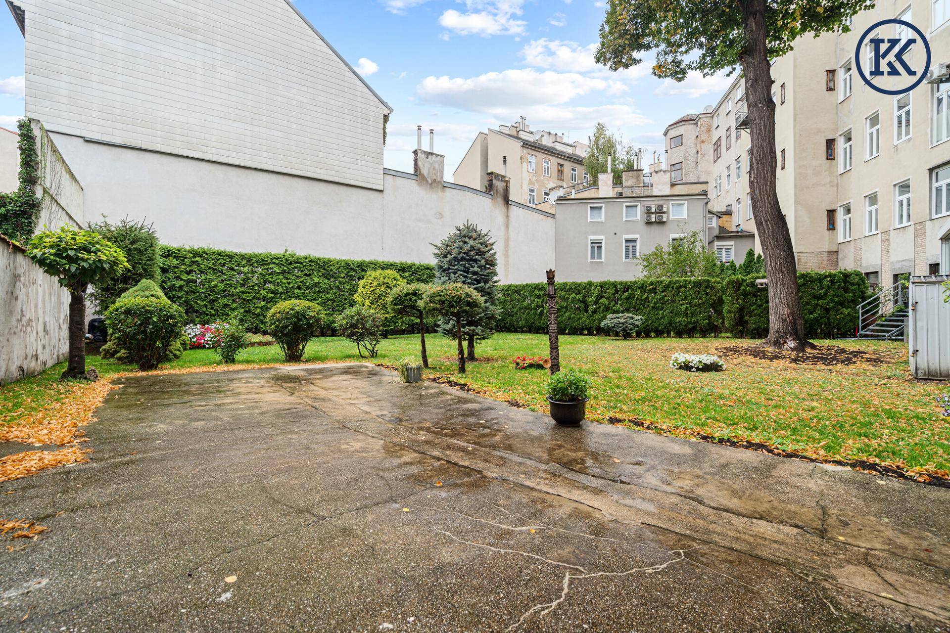 Gepflegter Gemeinschaftsgarten mit Rasenfläche, Bäumen und Hecken im Hinterhof.
