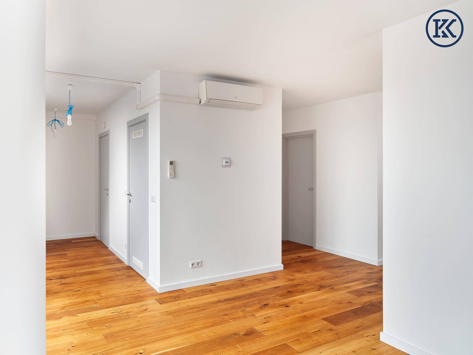 Geräumiger Flur mit Holzboden, weißen Wänden und mehreren Türen.