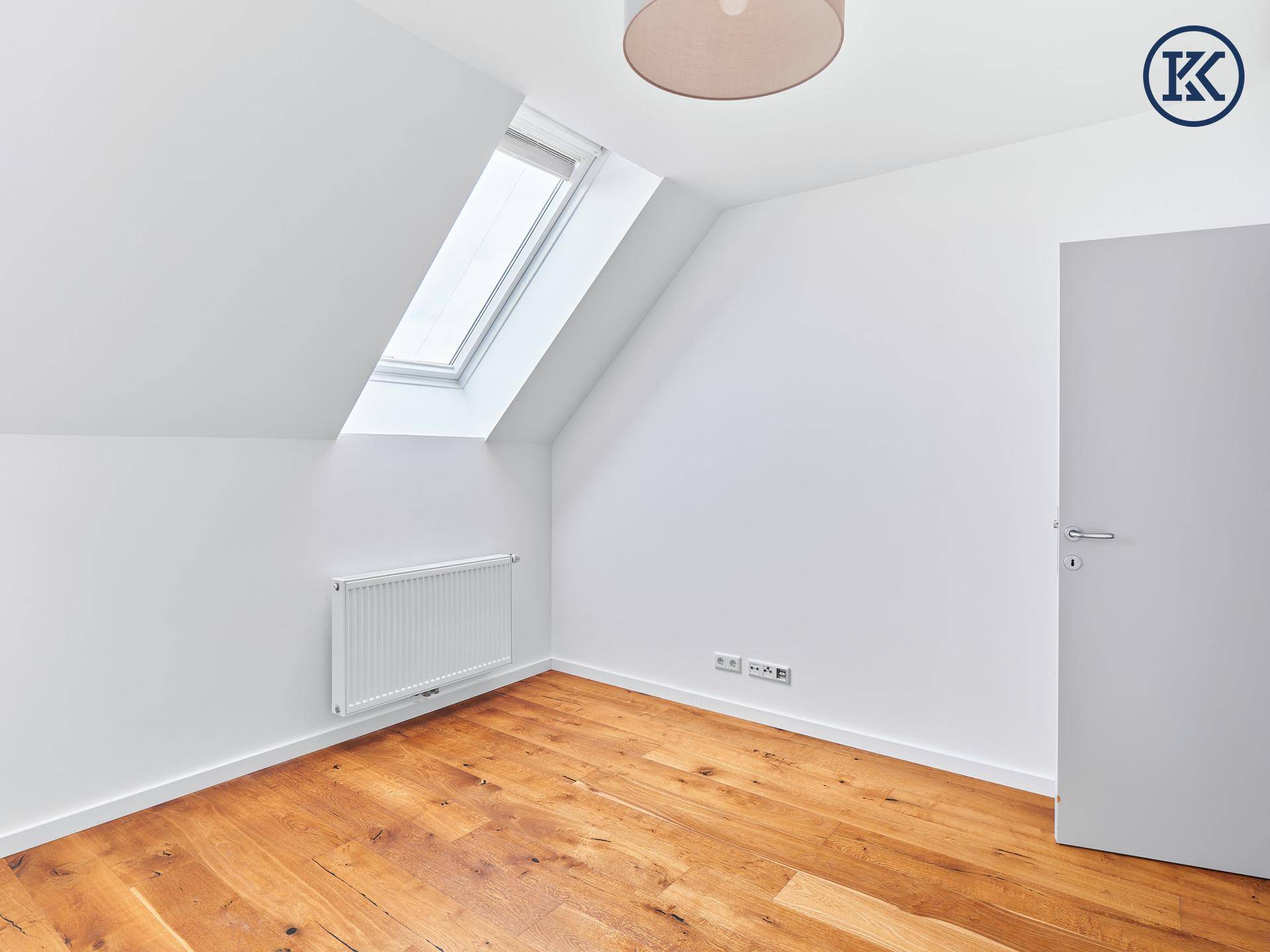 Helles Schlafzimmer mit Holzboden, Dachfenster und Heizkörper, ideal für ein Kinderzimmer.