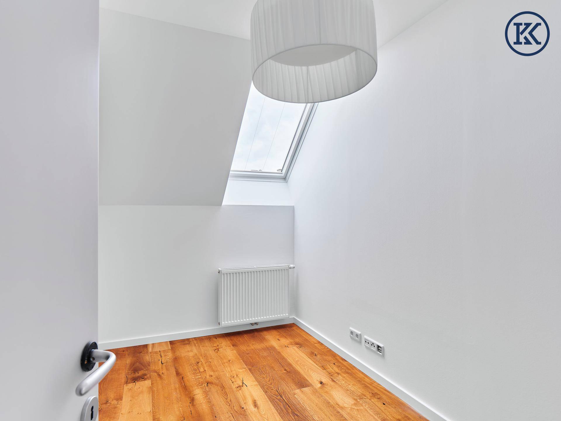 Kleines, helles Schlafzimmer mit Dachfenster, Holzboden und Heizkörper.