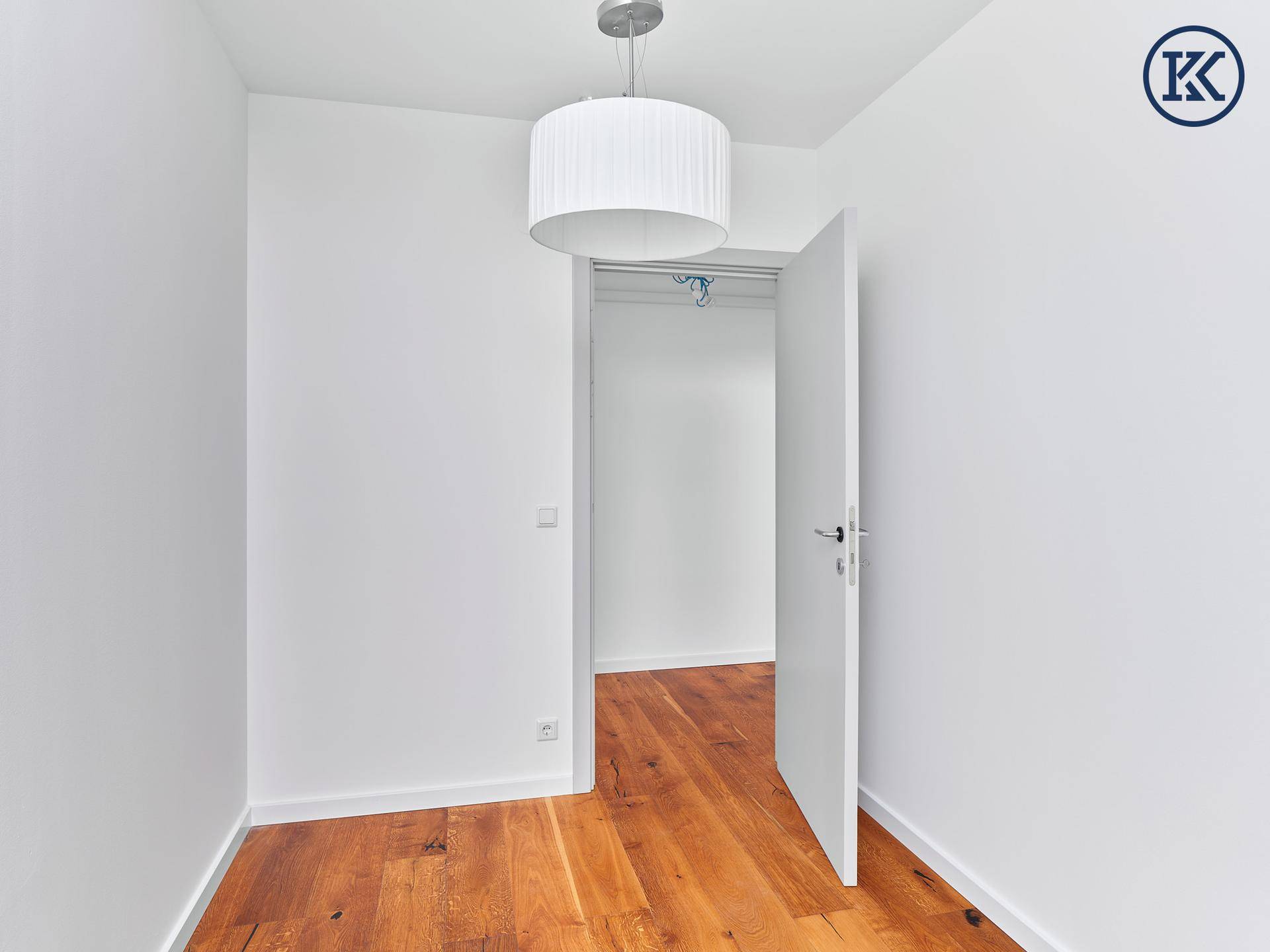 Helles Schlafzimmer mit Holzboden und Zugang zu einem begehbaren Kleiderschrank.