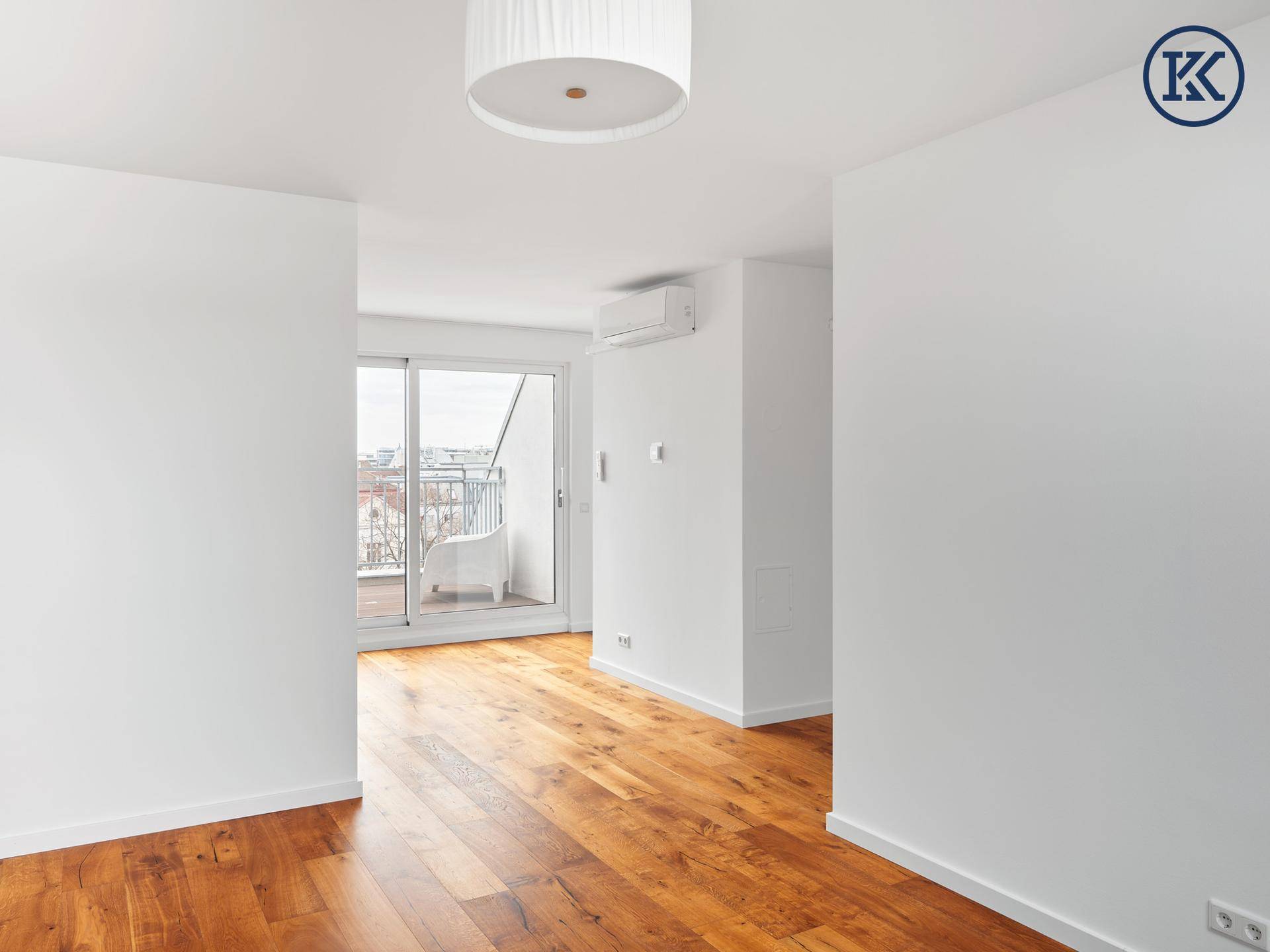 Heller Wohnraum mit Holzboden und Schiebetür zum Balkon, ausgestattet mit Klimaanlage.