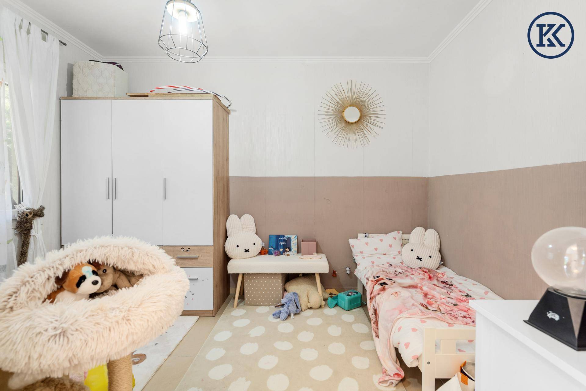 Kinderzimmer mit Einzelbett, Kleiderschrank und spielerischer Dekoration in hellen Farben.