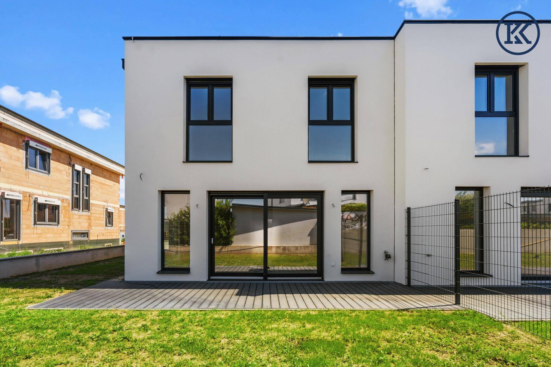 Rückseite eines modernen Neubaus mit großen Schiebetüren und Gartenblick.