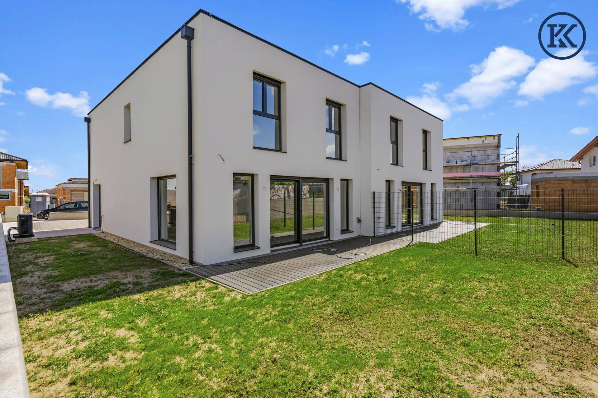 Rückansicht eines modernen Neubaus mit großen Fenstern und Zugang zum Garten.