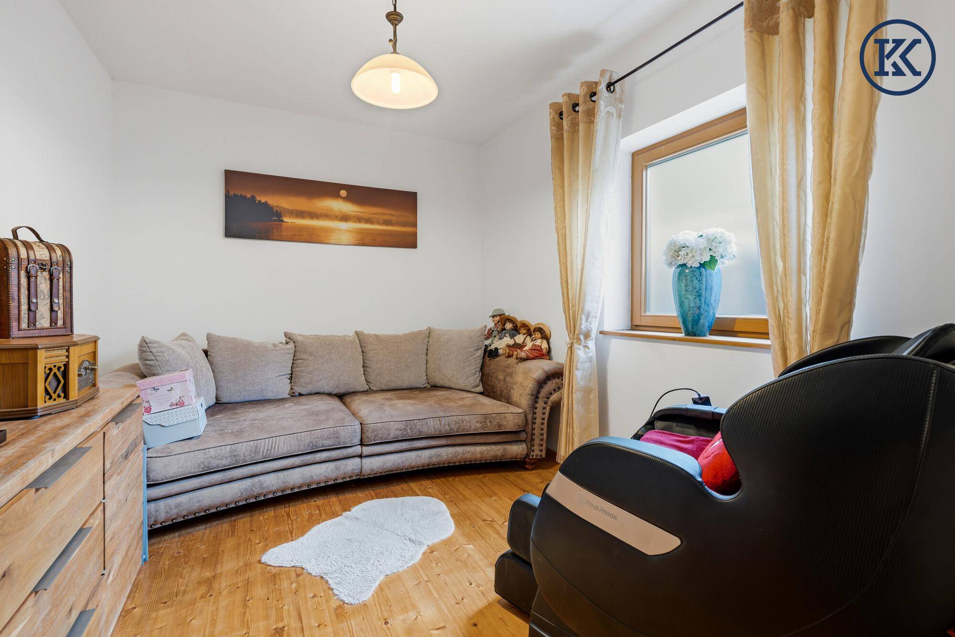 Gemütliches Wohnzimmer mit beigem Sofa, Holzboden und einem Fenster mit Vorhängen.