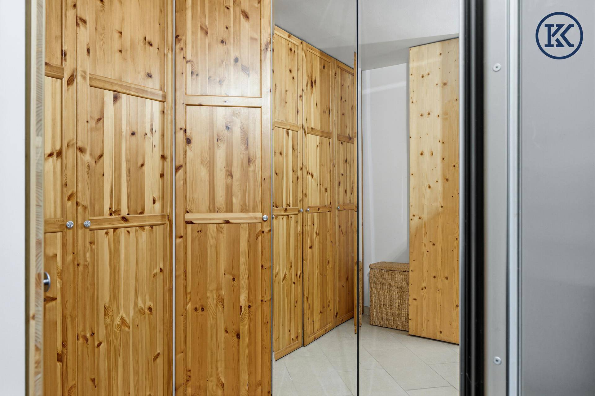 Geräumiger begehbarer Kleiderschrank mit Holzschränken und Spiegeltüren.
