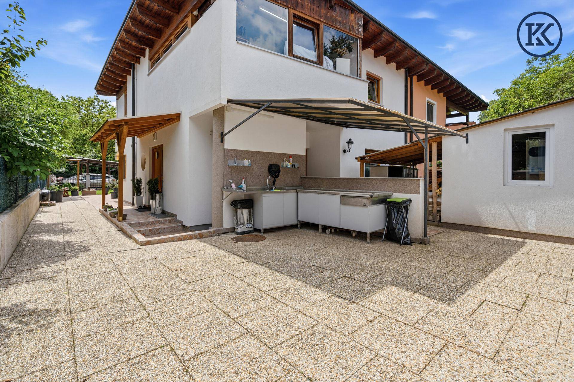 Überdachte Außenküche mit Spülbecken und Arbeitsfläche neben dem Haus.