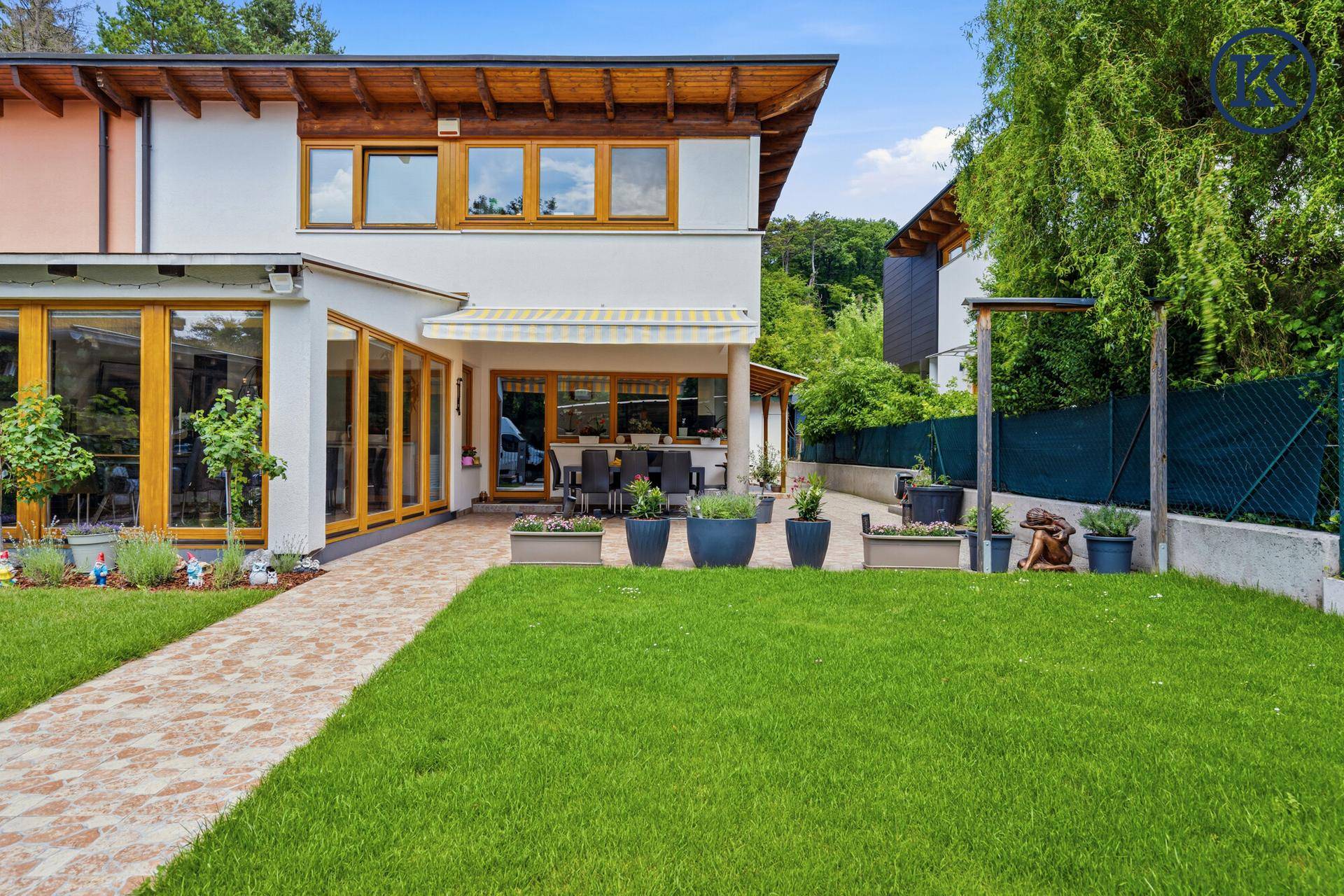 Gepflegter Garten mit Rasenfläche, Blumenbeeten und einer großen Terrasse.