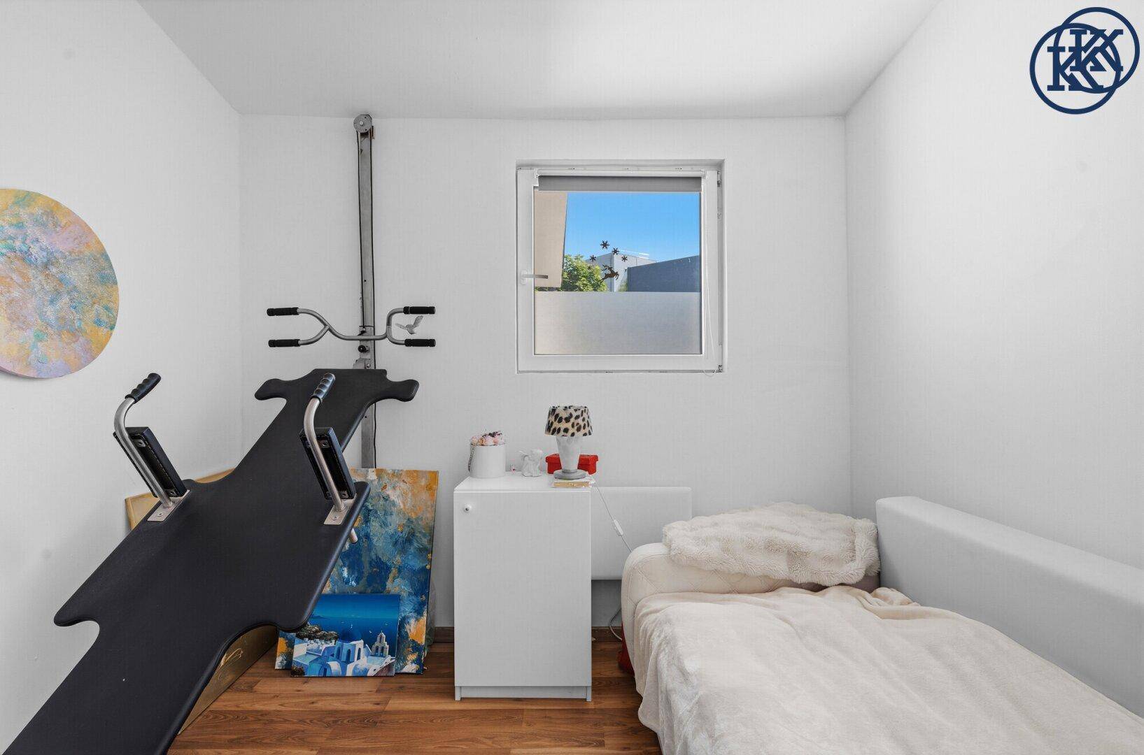 Helles Schlafzimmer mit Holzboden, Einzelbett und einem Fenster mit Blick nach draußen.