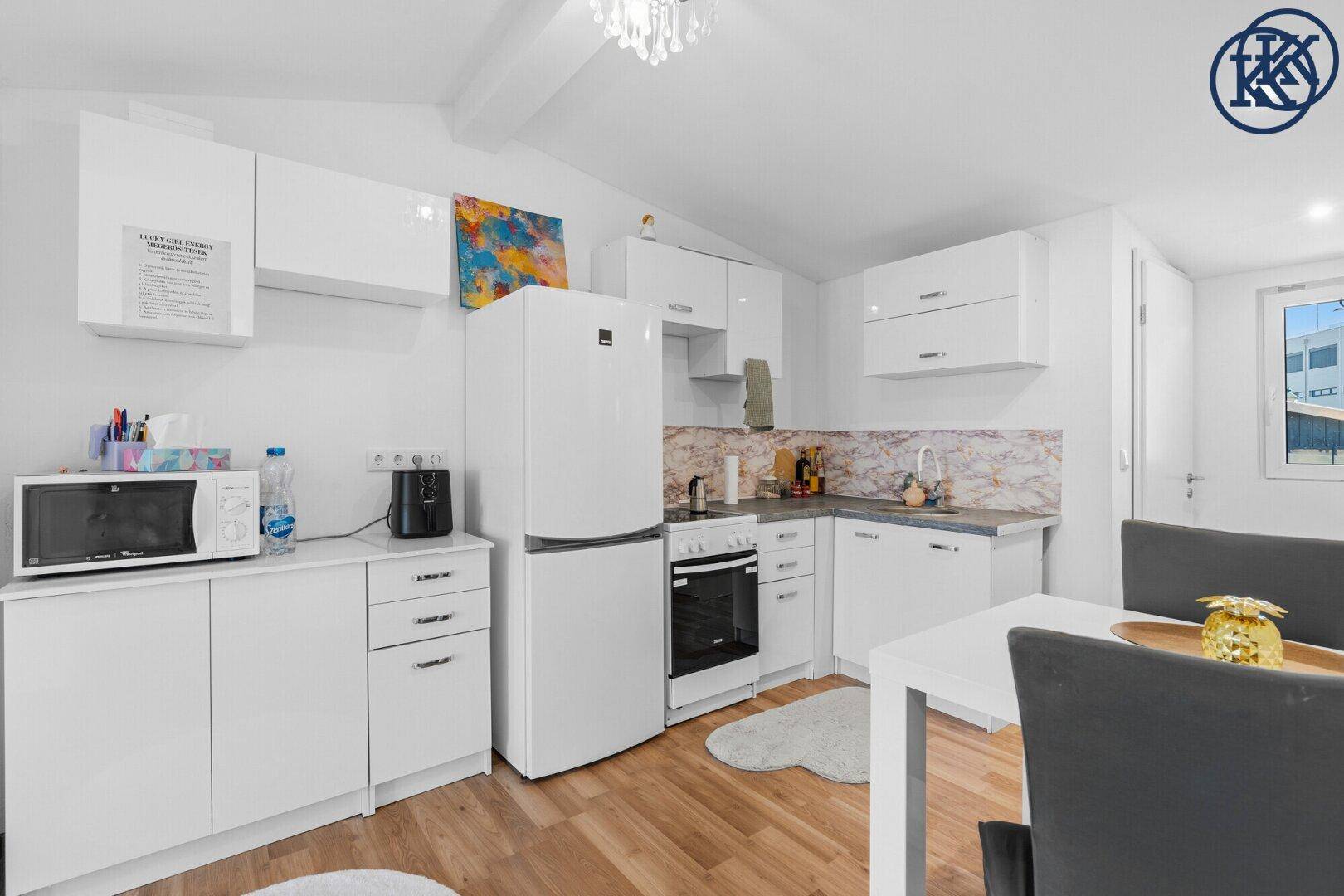 Funktionale weiße Küche mit Kühlschrank, Backofen und Mikrowelle, sowie Essbereich.