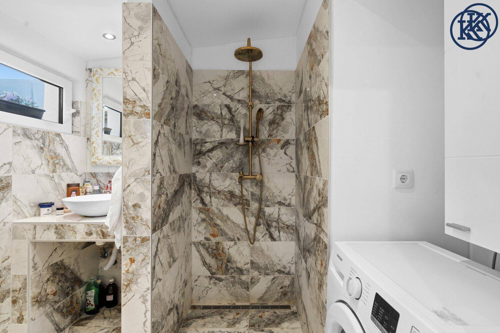 Modernes Badezimmer mit begehbarer Dusche, Marmorfliesen und Waschmaschine.