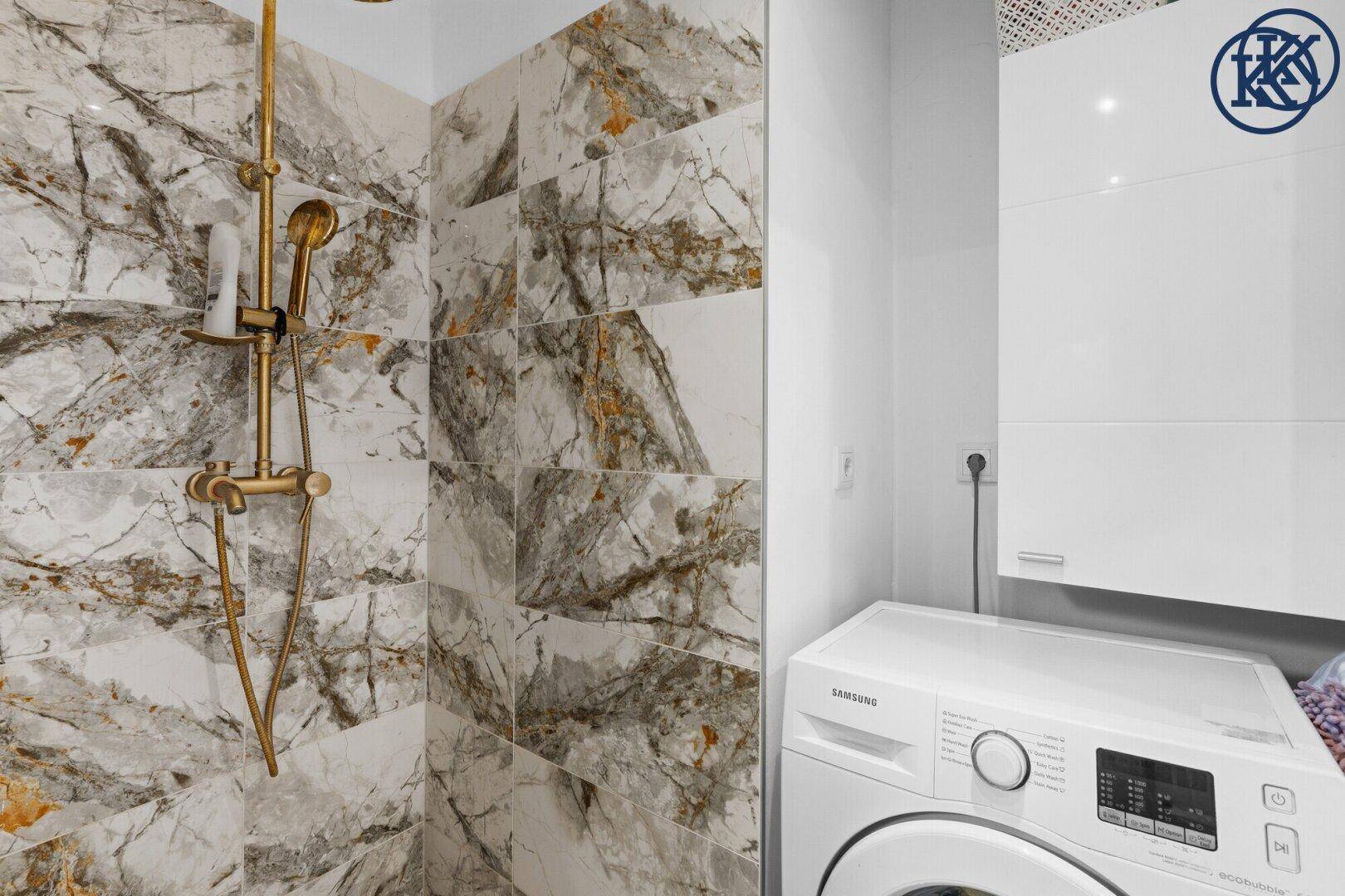 Begehbare Dusche mit luxuriösen Marmorfliesen und einer praktischen Waschmaschine im Badezimmer.
