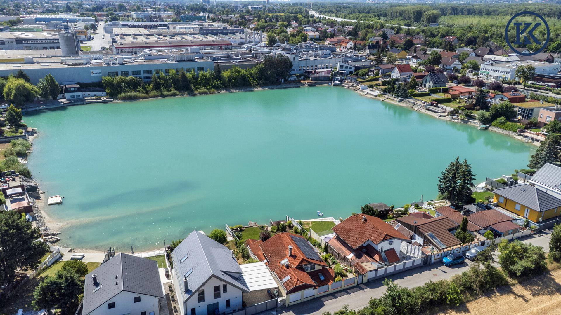 Panoramablick aus der Luft auf den großen See, umgeben von Wohngebäuden und Industrie.