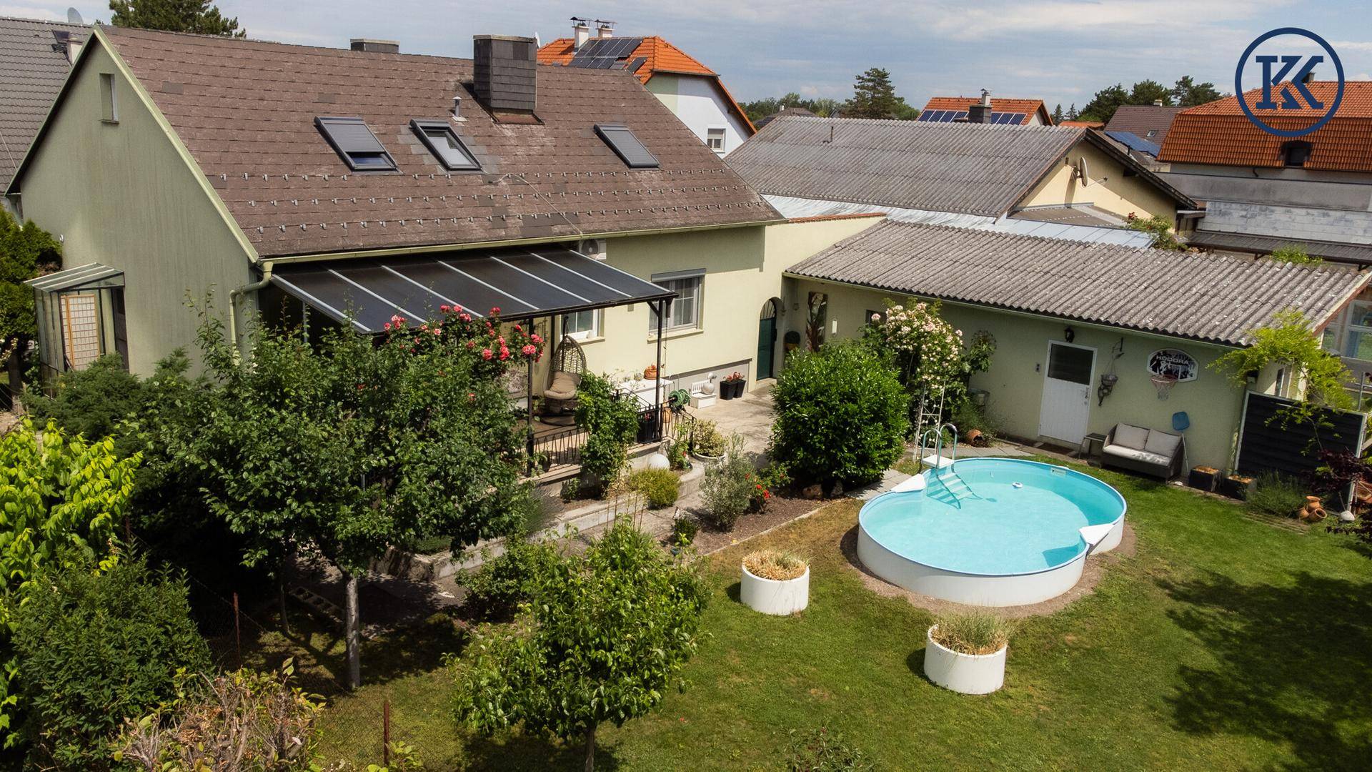 Weitläufiger Blick auf das Haus mit Garten, Pool und überdachter Terrasse in einer ruhigen Wohngegend.