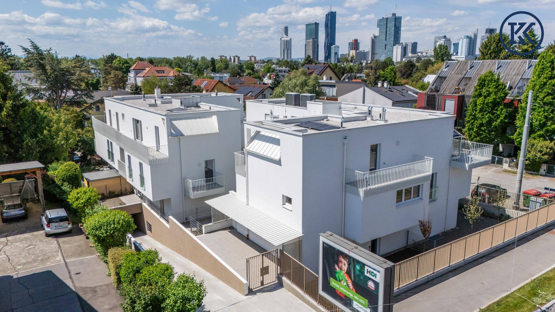 Panoramablick auf das moderne Gebäude mit Flachdach und die umliegende Nachbarschaft mit Stadtblick im Hintergrund.