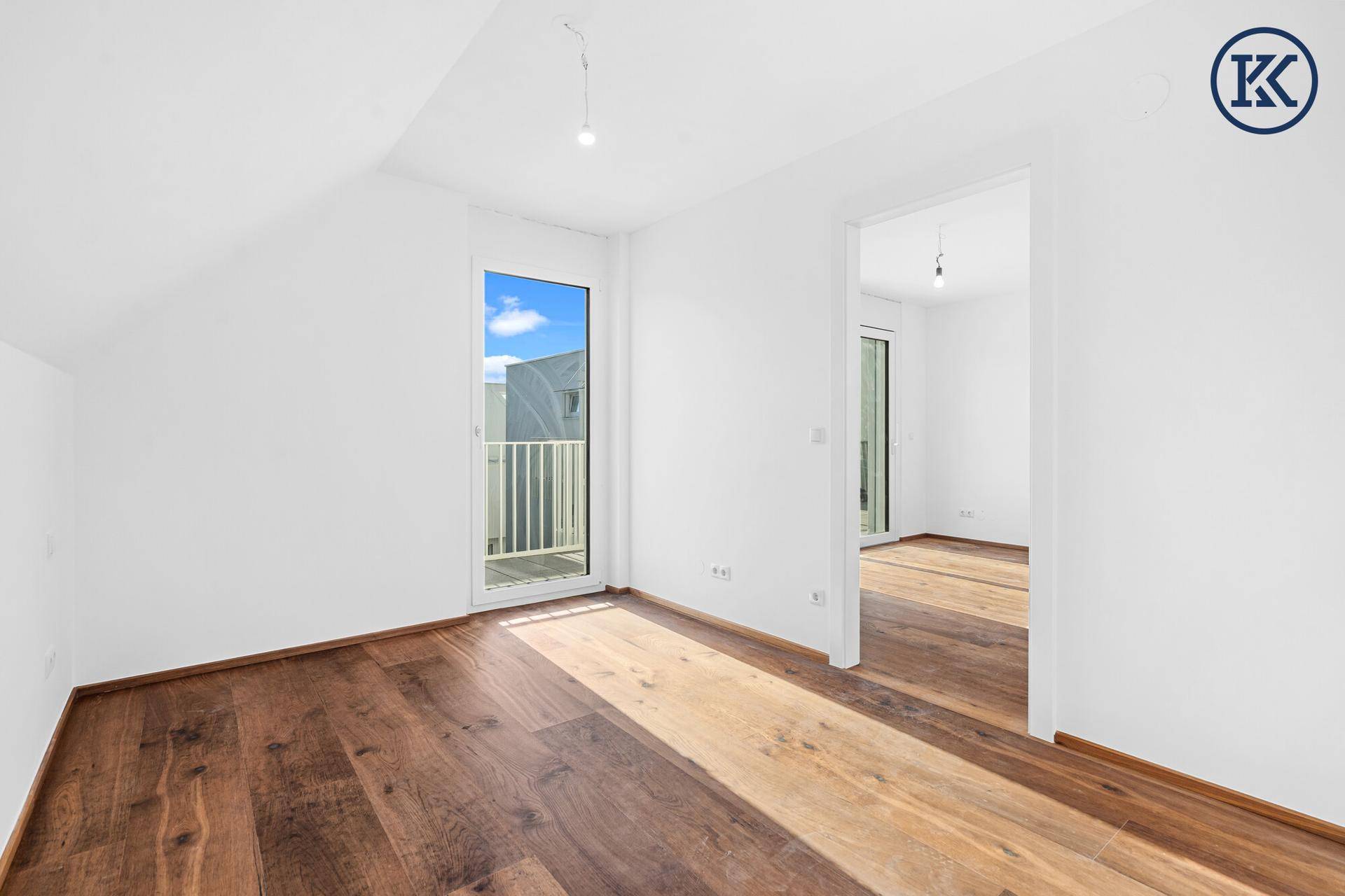 Helles Schlafzimmer mit Holzboden und Zugang zu einem französischen Balkon.
