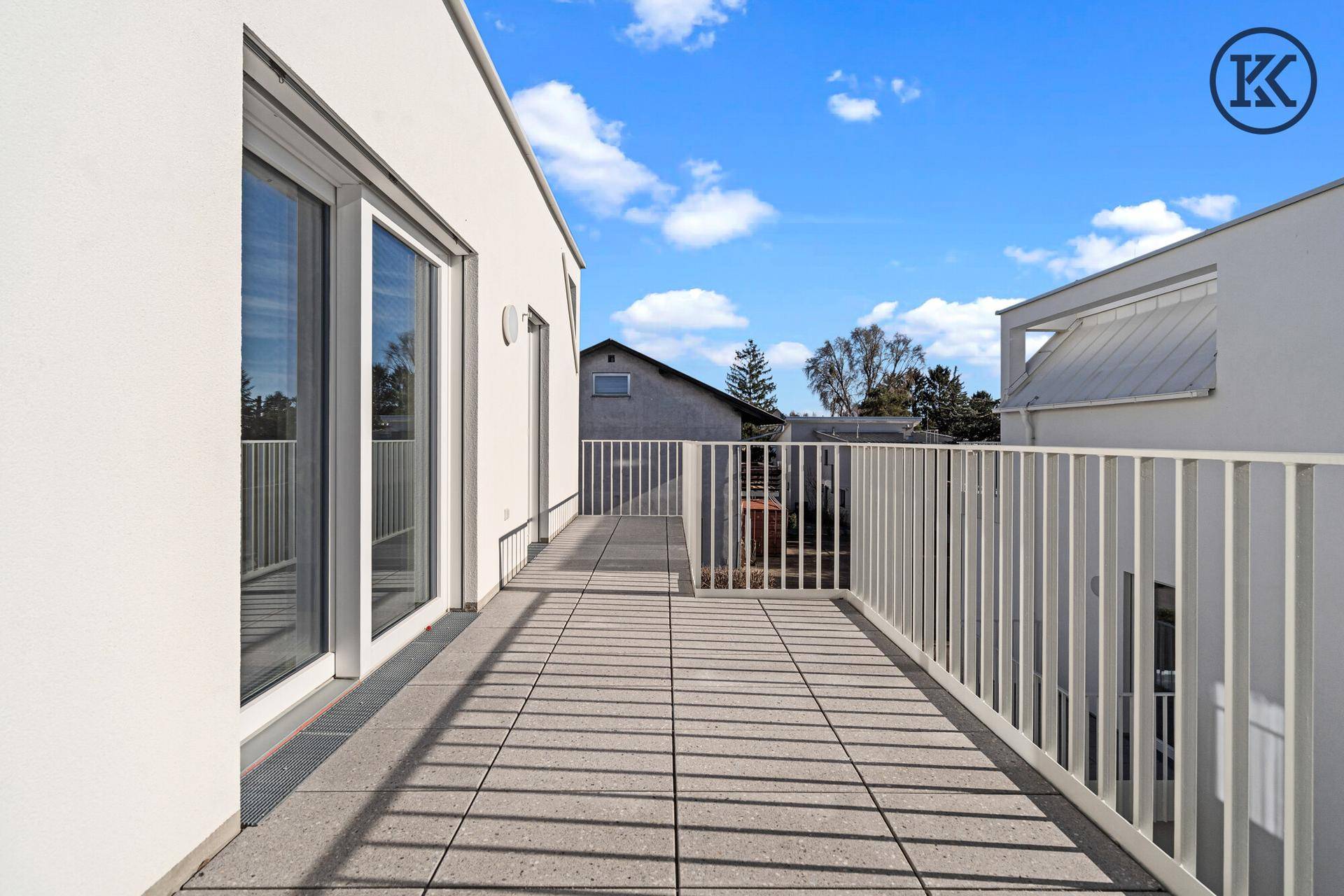 Geräumiger Balkon mit Fliesenboden und weißem Geländer, ideal für entspannte Stunden im Freien.