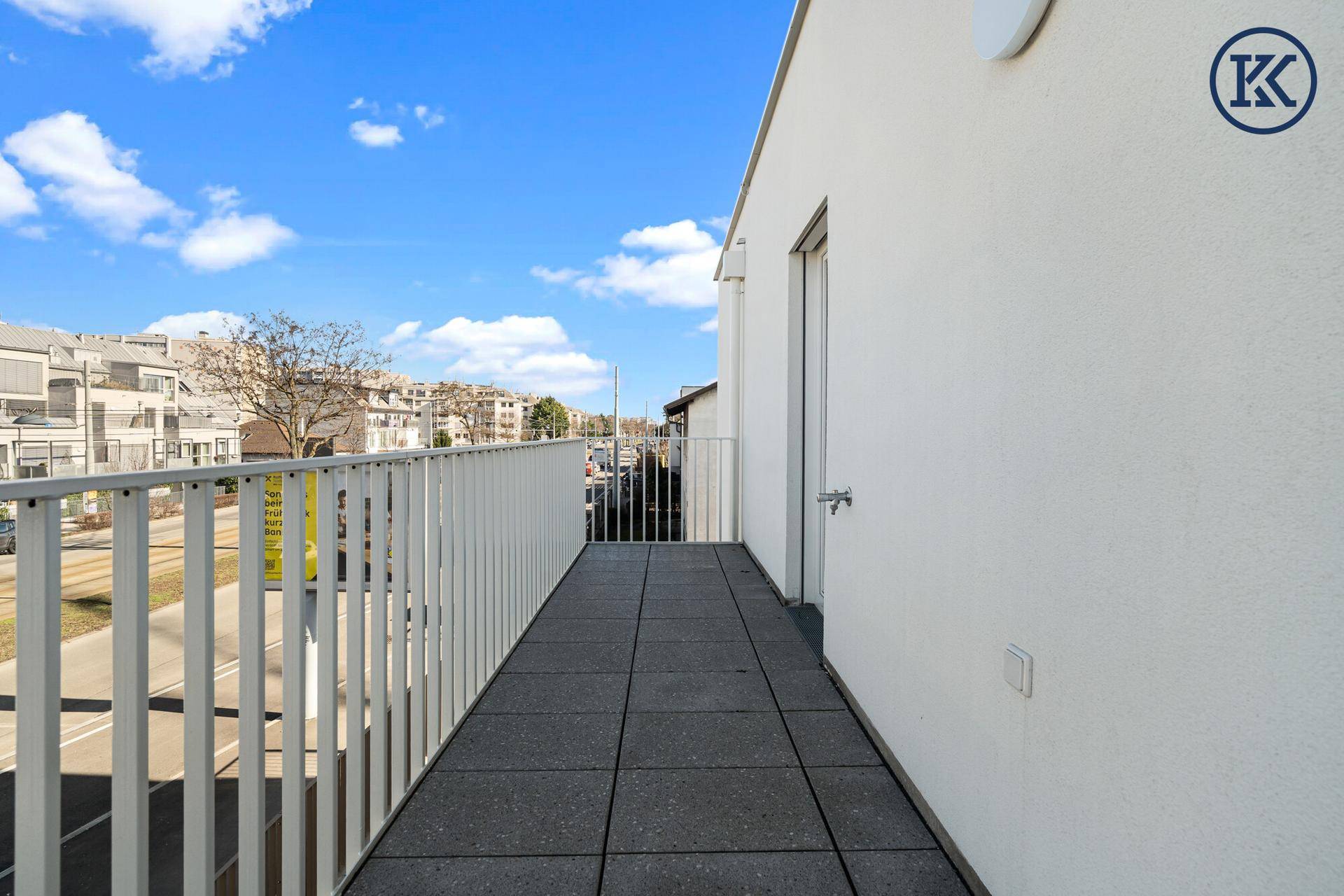 Langer, schmaler Balkon mit Fliesenboden und weißem Geländer, bietet Blick auf die Umgebung.