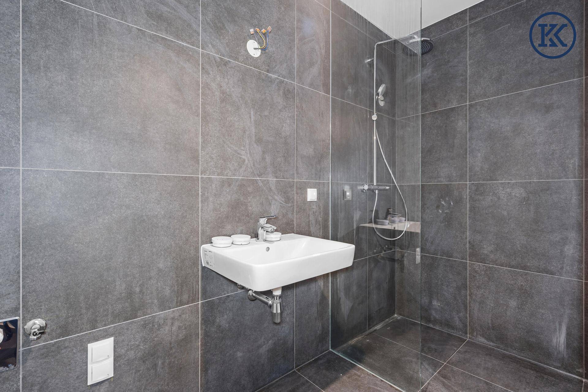 Zeitgemäßes Badezimmer mit grauen Fliesen, einer Glasdusche und einem eleganten Waschbecken.