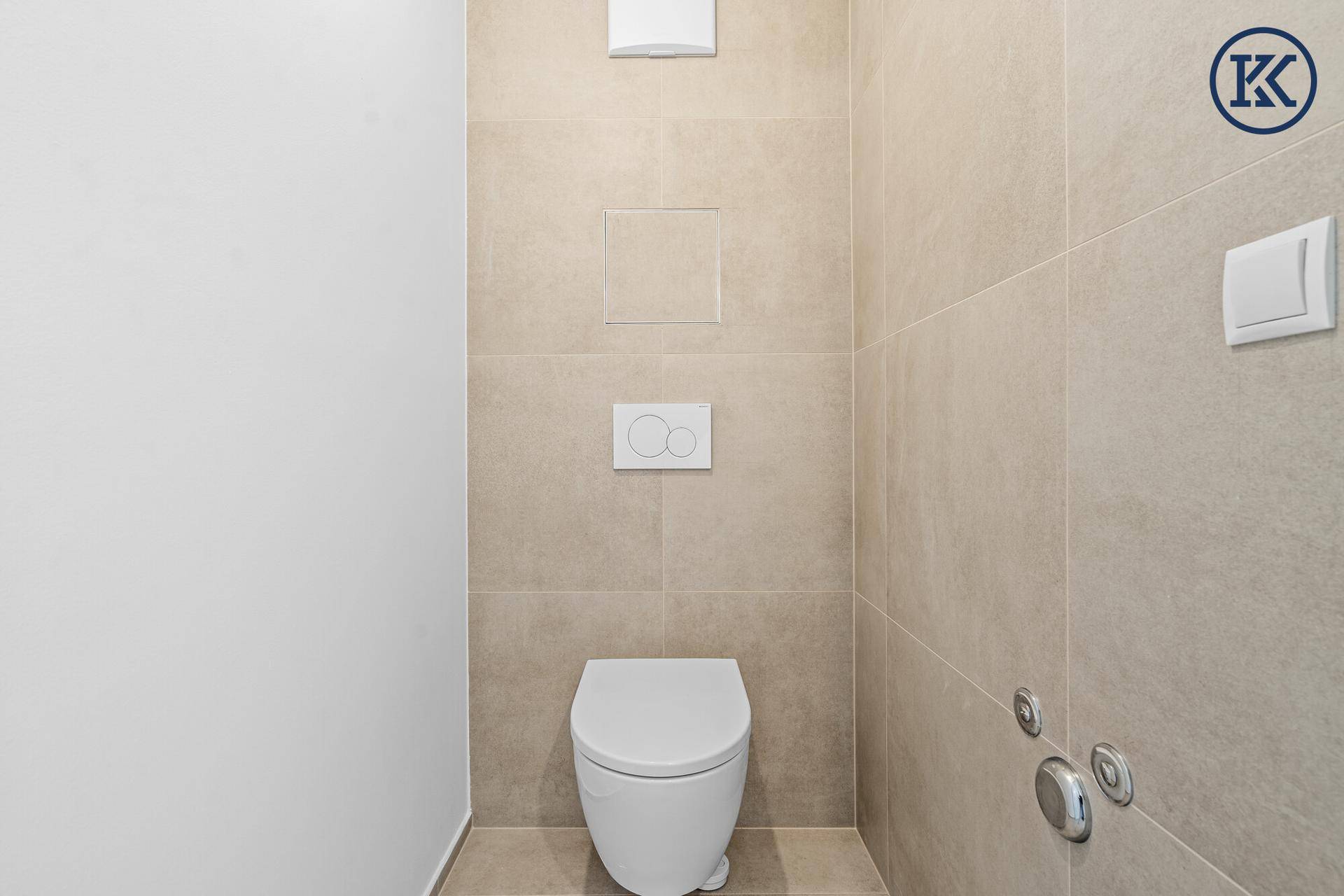 Modernes WC mit wandhängender Toilette und beigefarbenen großformatigen Fliesen.