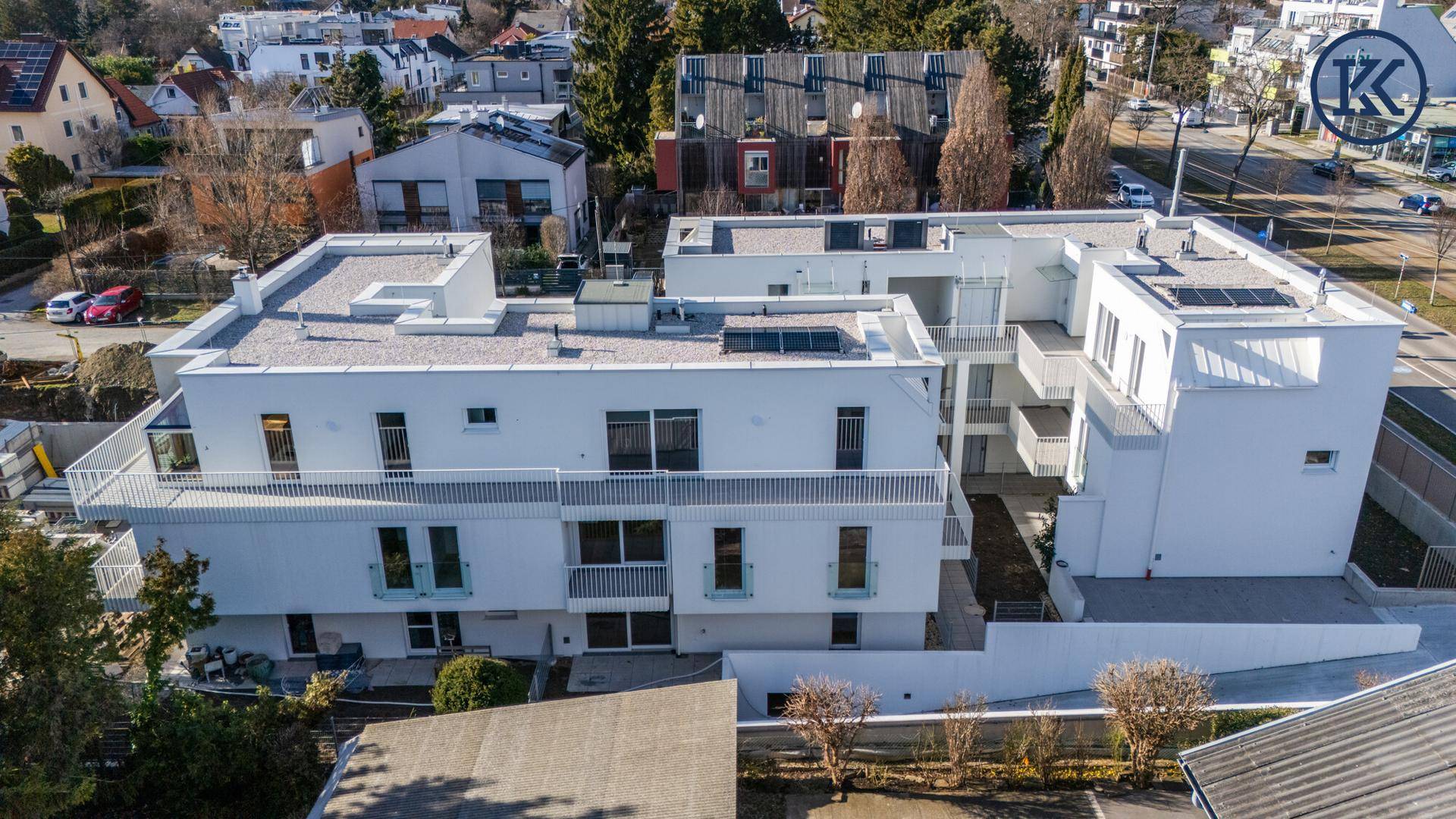 Luftaufnahme eines modernen, weißen Neubaukomplexes mit mehreren Balkonen und Flachdächern.
