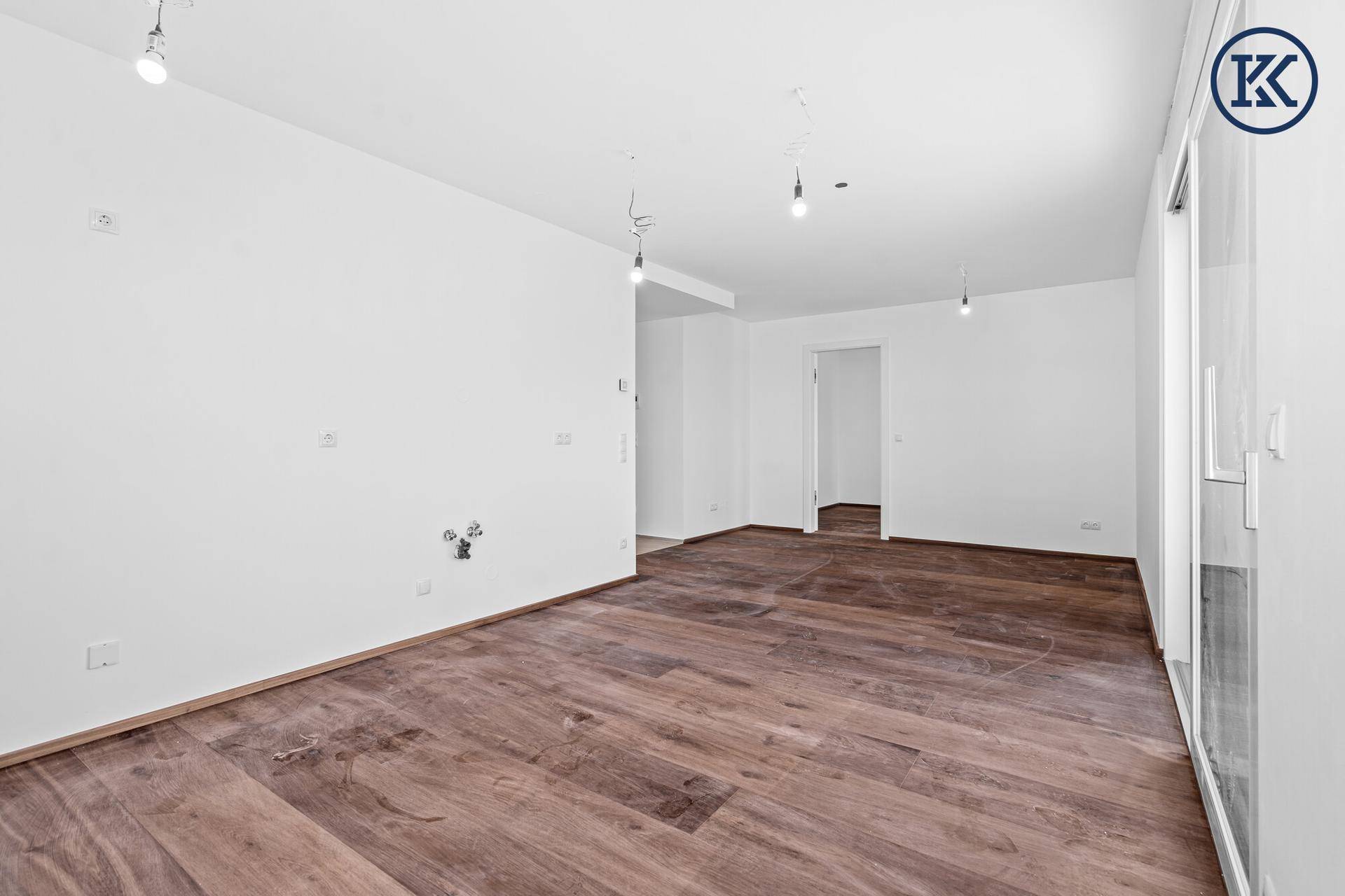 Leeres Zimmer mit dunklem Holzboden und weißen Wänden, bereit für individuelle Gestaltung.