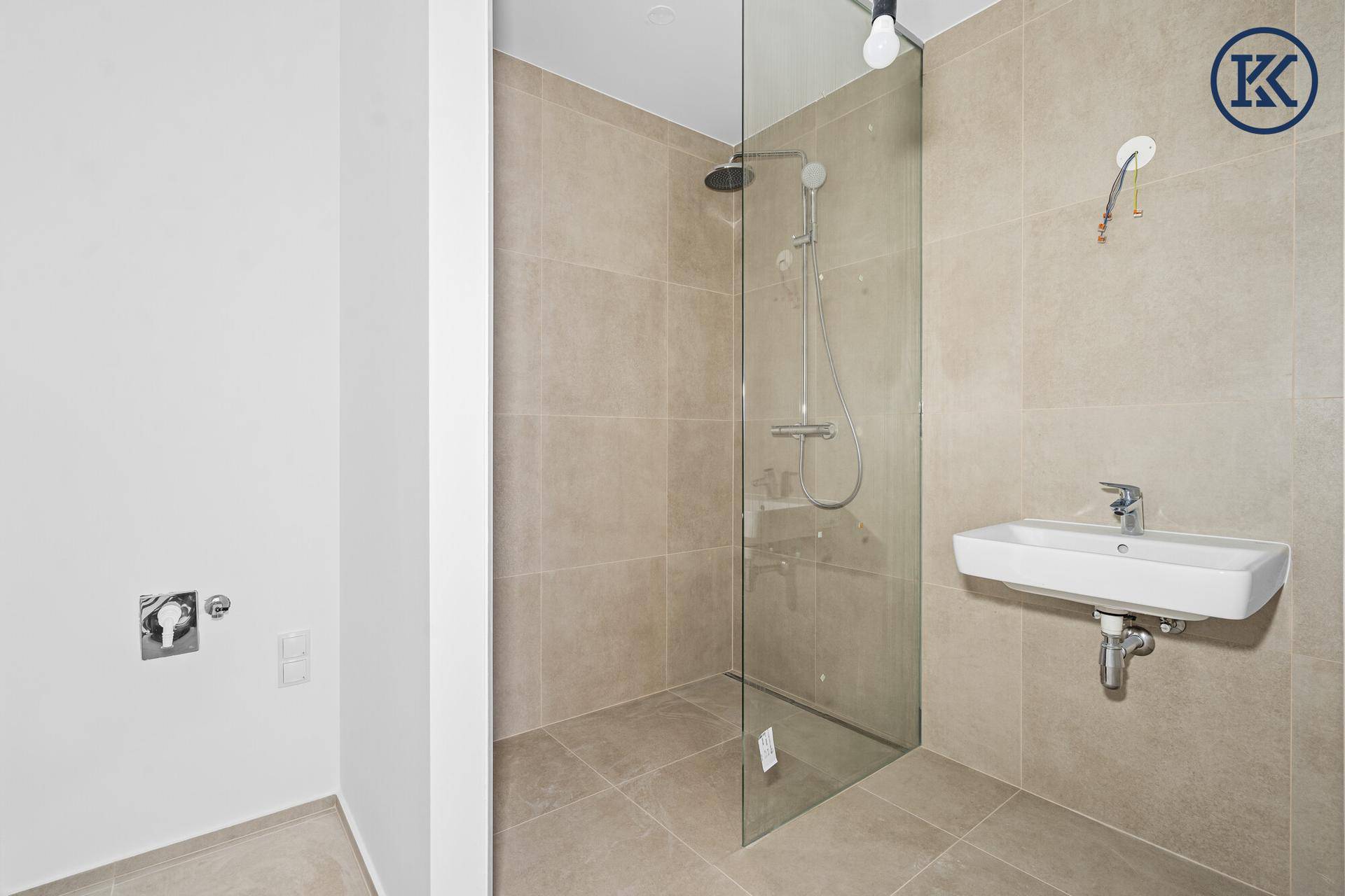Modernes Badezimmer mit begehbarer Dusche, Glasabtrennung und einem einzelnen Waschbecken.