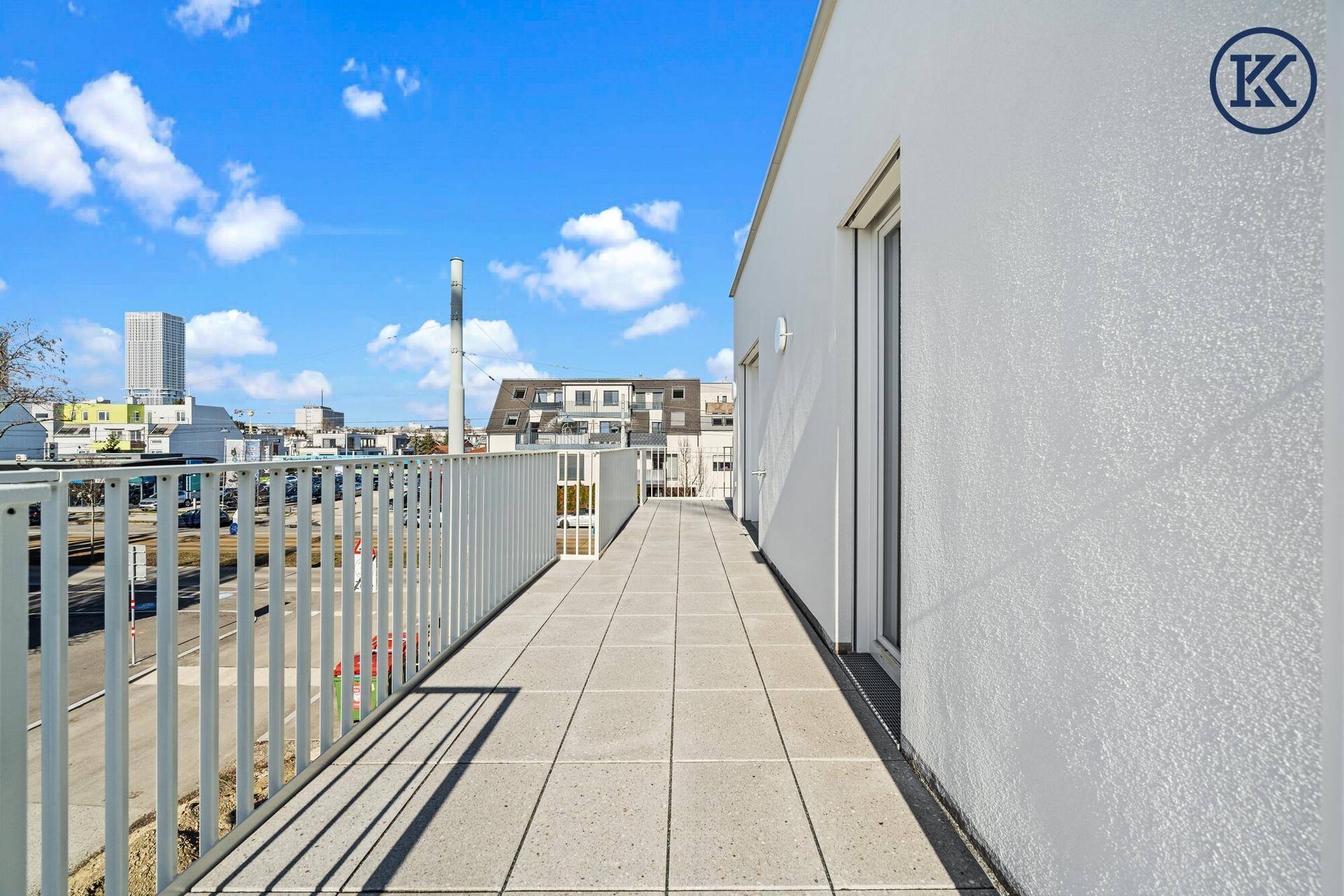 Weiterer Abschnitt des langen Balkons mit Fliesenboden und Blick auf die Umgebung.