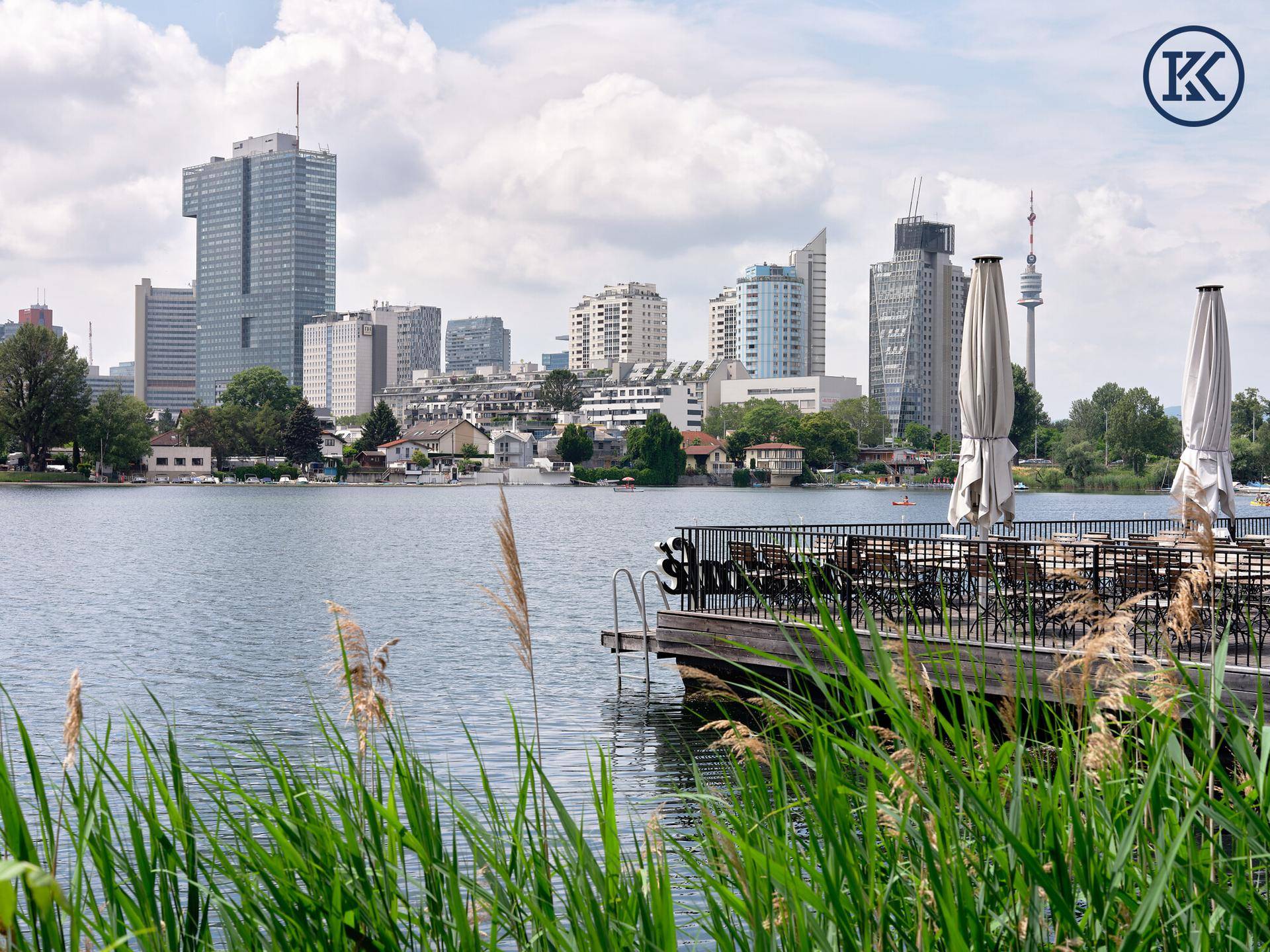 Panoramablick auf den See mit der beeindruckenden Wiener Skyline und einem Restaurantsteg.