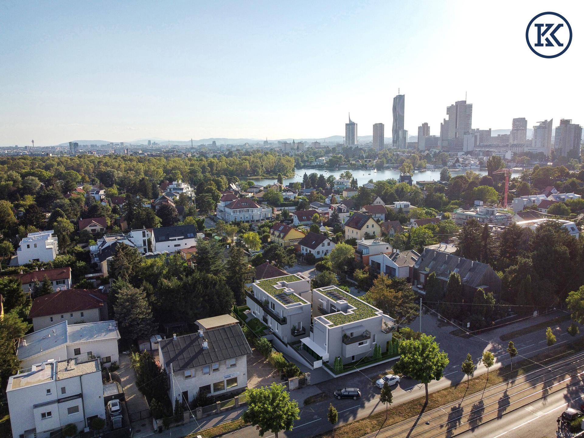 Luftaufnahme der Wohngegend mit dem Neubau und der Wiener Skyline im Hintergrund.