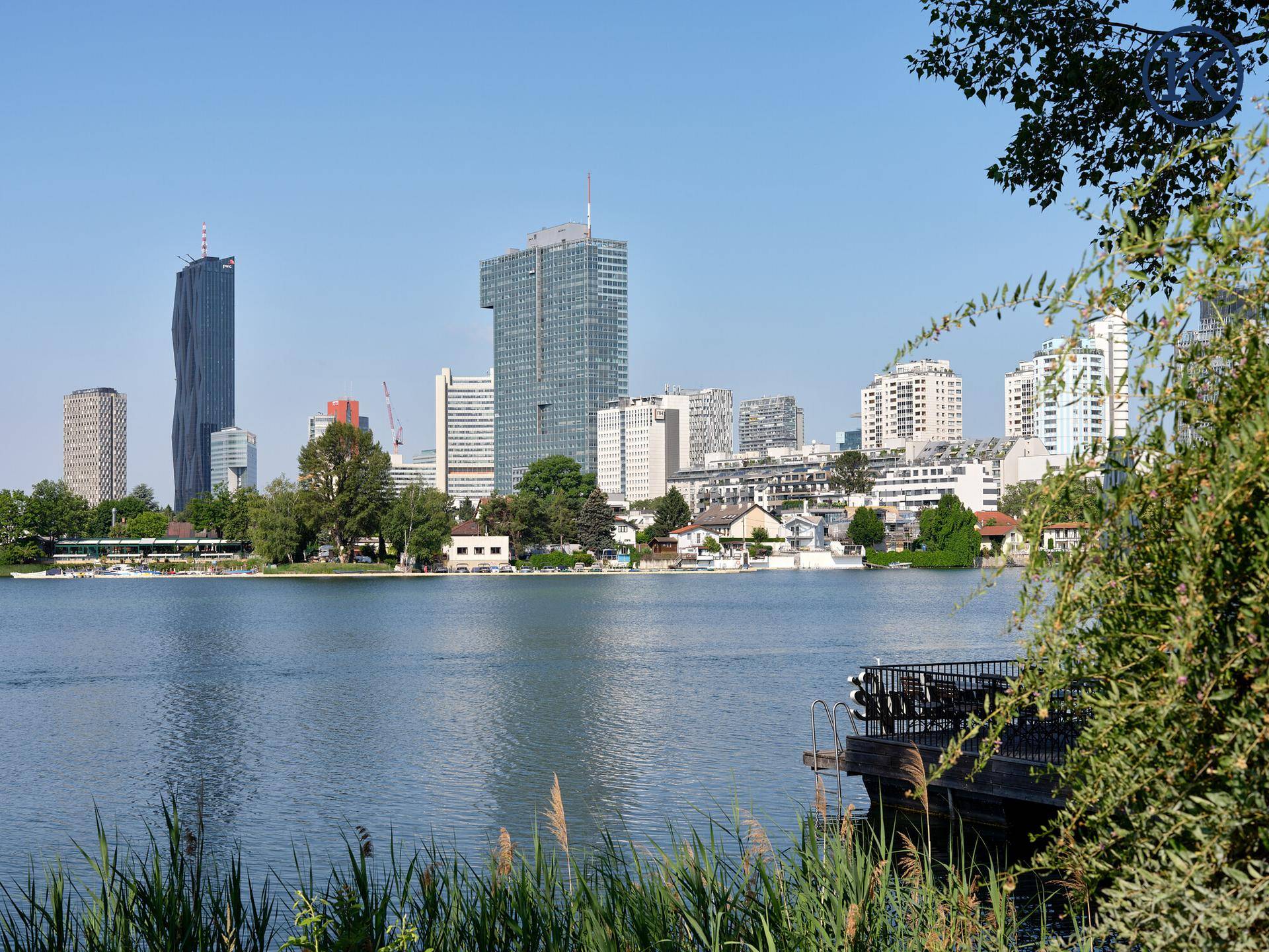 Sonniger Blick über den See zur beeindruckenden Wiener Skyline mit modernen Hochhäusern.
