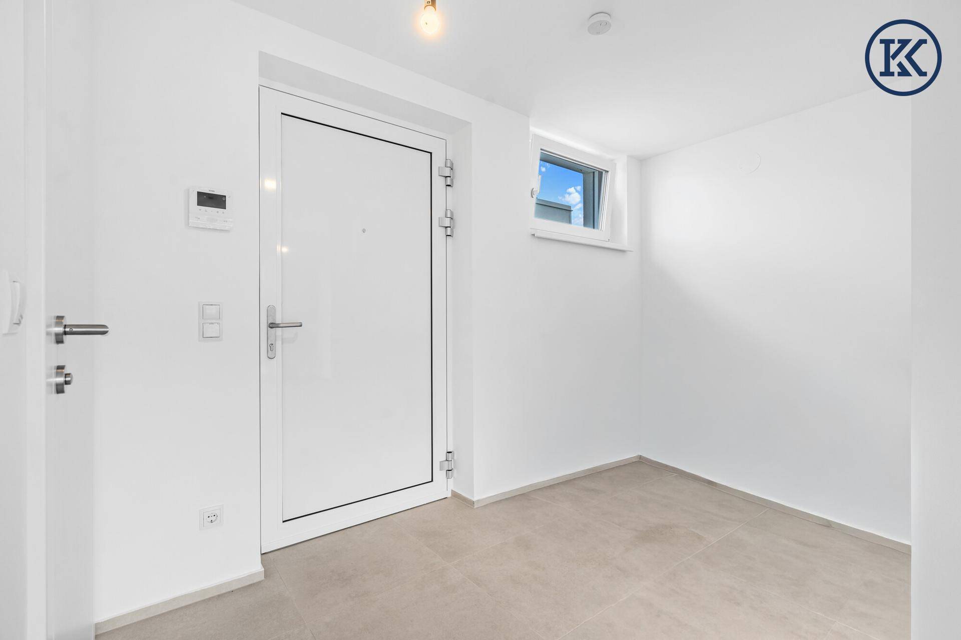 Heller Eingangsbereich mit moderner weißer Tür, Fliesenboden und einem kleinen Fenster.