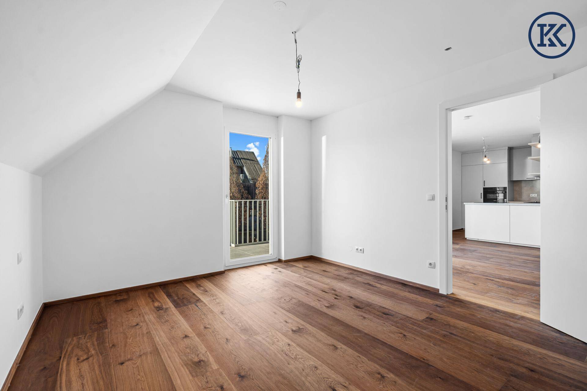 Helles Schlafzimmer mit Holzboden, Dachschräge und Zugang zu einem kleinen Balkon.