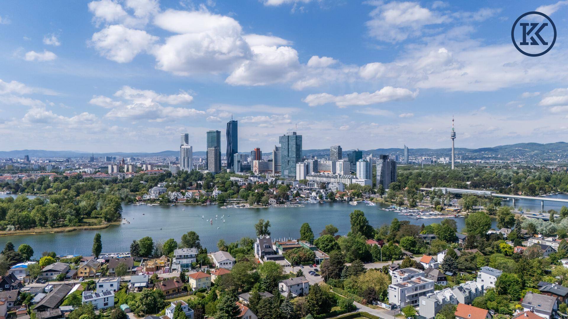 Panoramablick aus der Vogelperspektive auf die Donau City, den See und die umliegende Wohnbebauung.