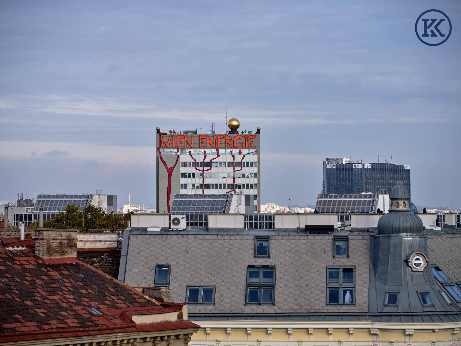Stadtansicht mit einem großen Gebäude, das "Wien Energie" zeigt, und Solarpaneelen auf Dächern.
