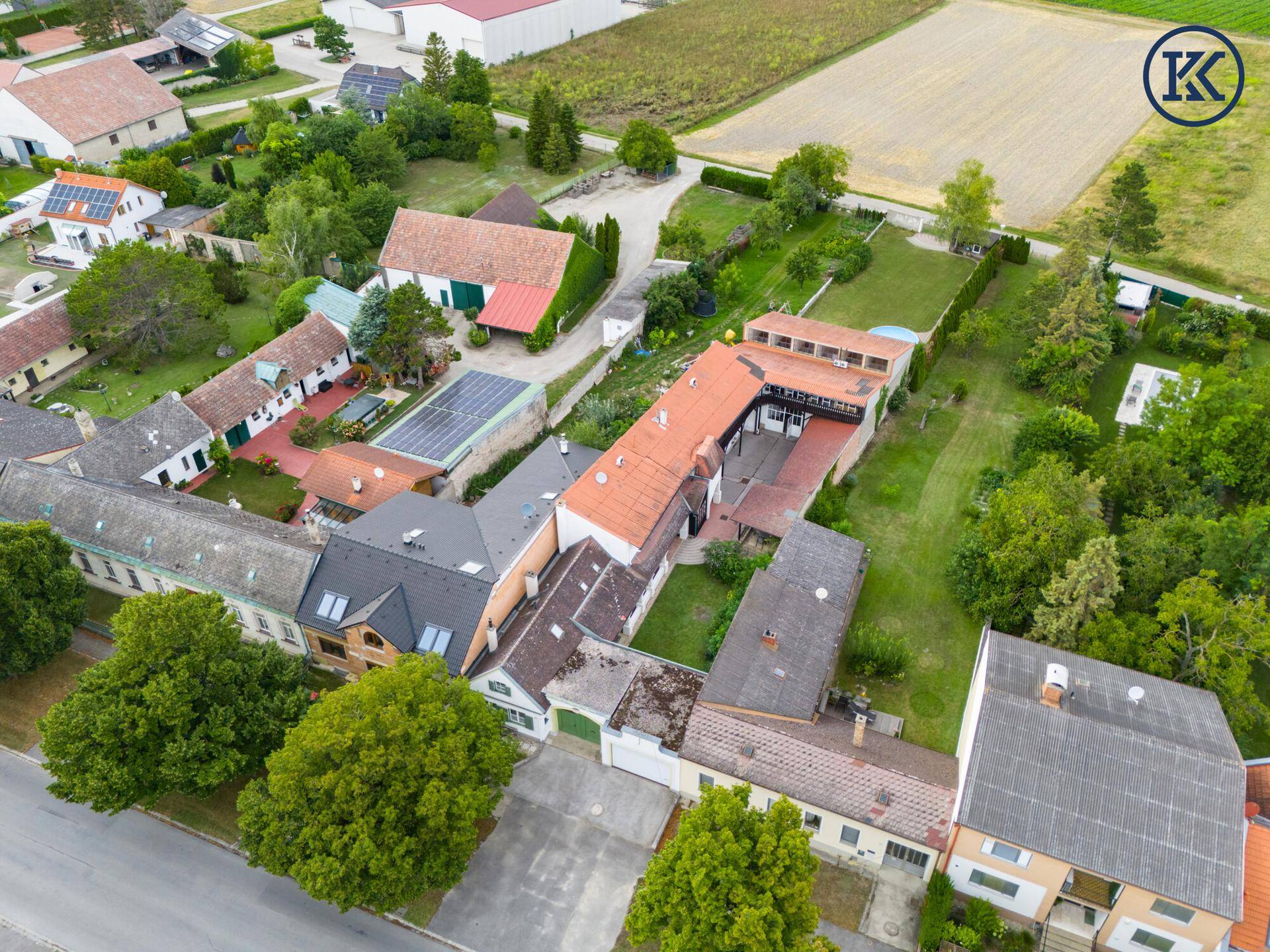 Luftaufnahme des gesamten Anwesens mit umliegenden Feldern und Nachbarhäusern.